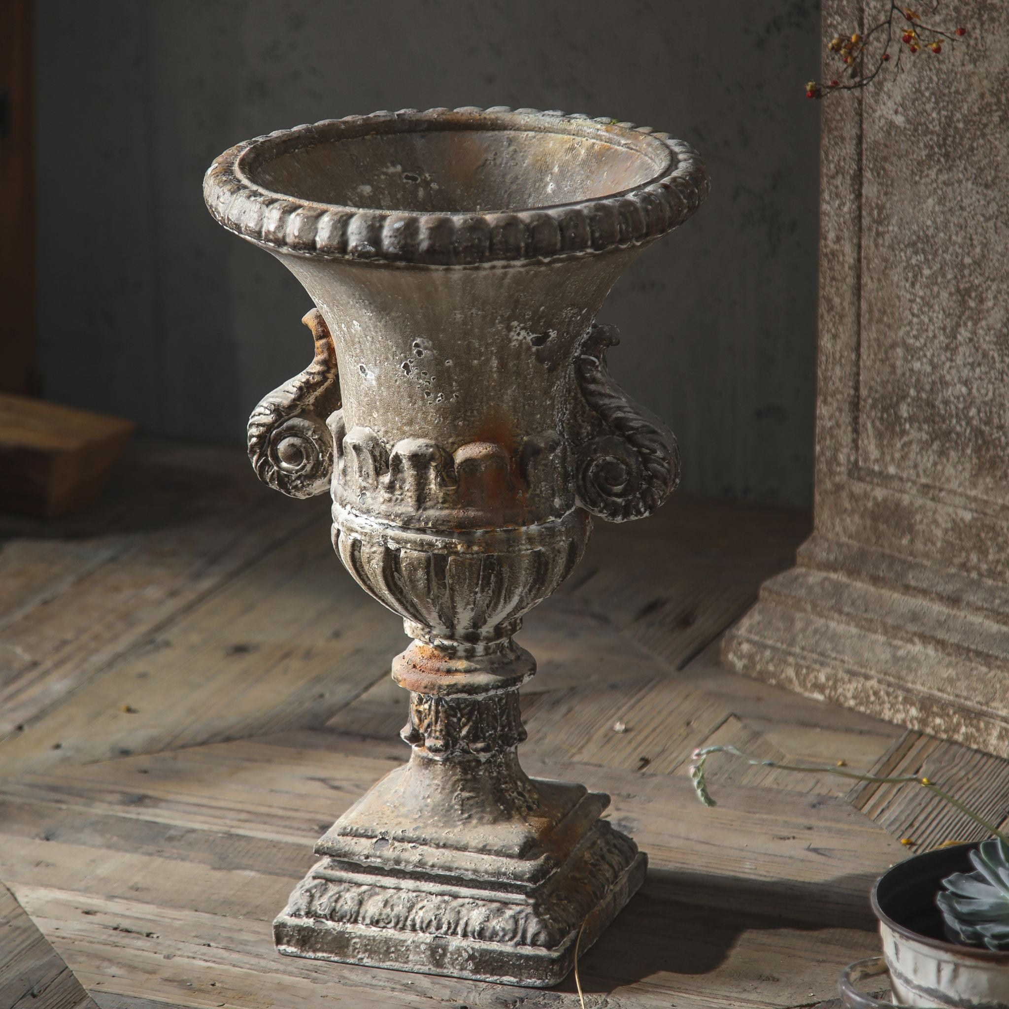 Emilie urn planter shown empty, scrolled handles, gadrooned rim, fluted bowl and square plinth.