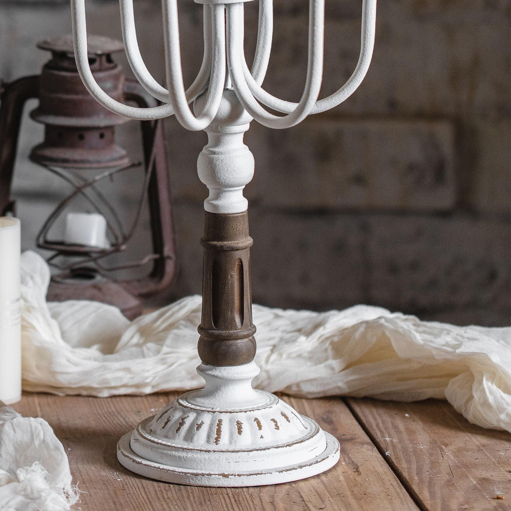 Close-up detail of Étienne candelabra's turned wood column base, showing the distressed wood section with carved cut-outs and ribbed whitewashed pedestal foot