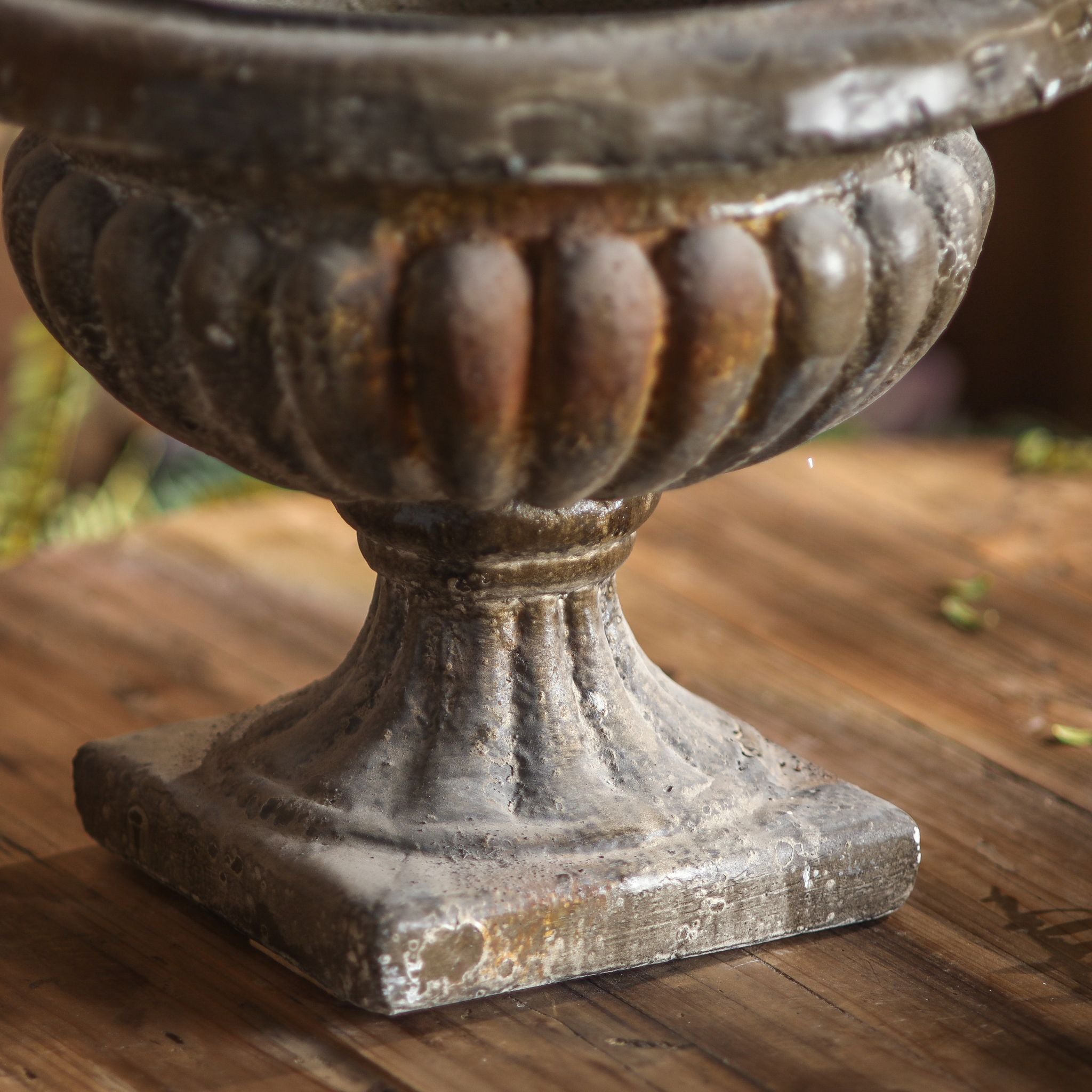 Close-up of the Évangéline urn gadrooned bowl, fluted stem and plinth in a rust-toned weathered patina.