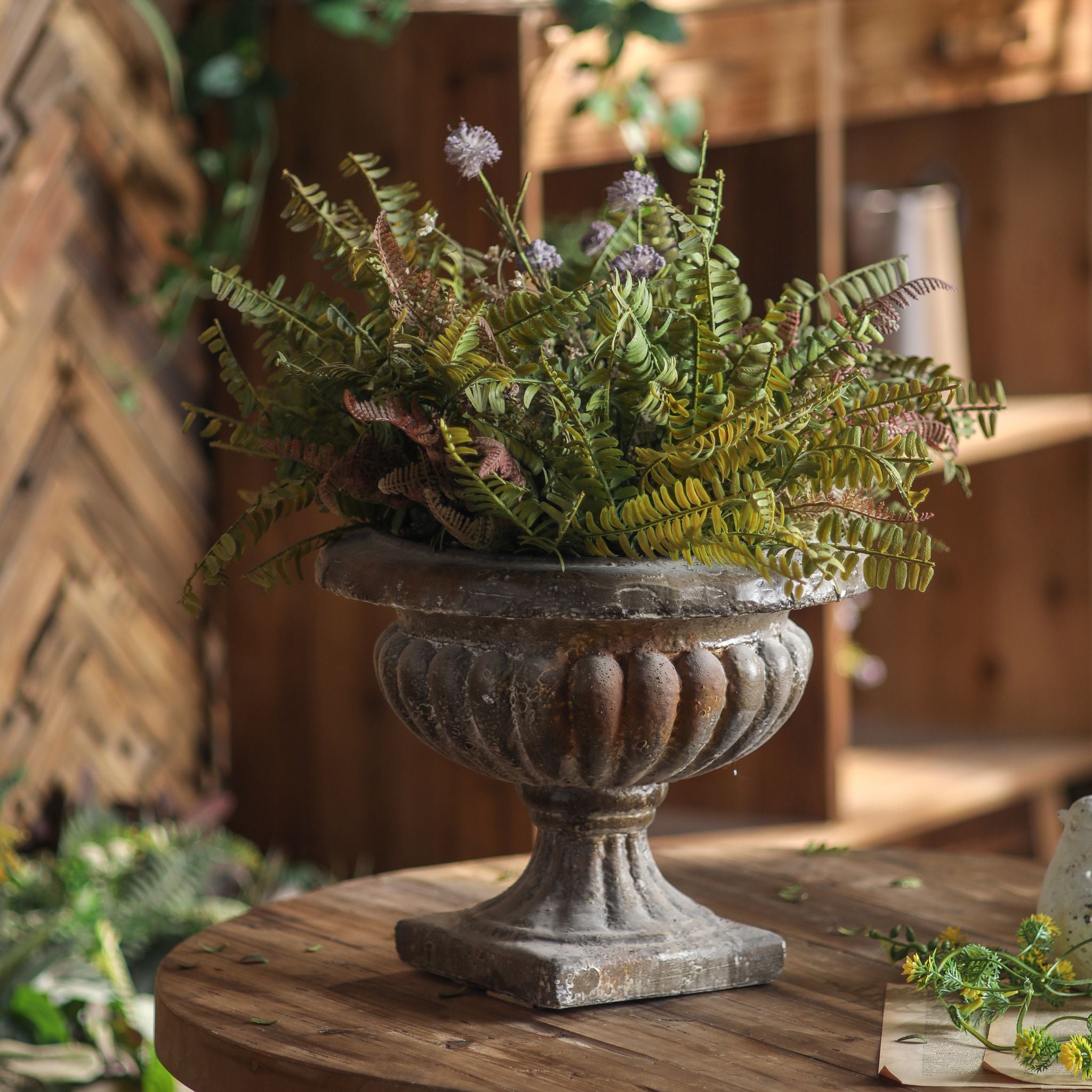 Évangéline compote urn planter styled with ferns and purple flowers as a table centrepiece.. Hero.