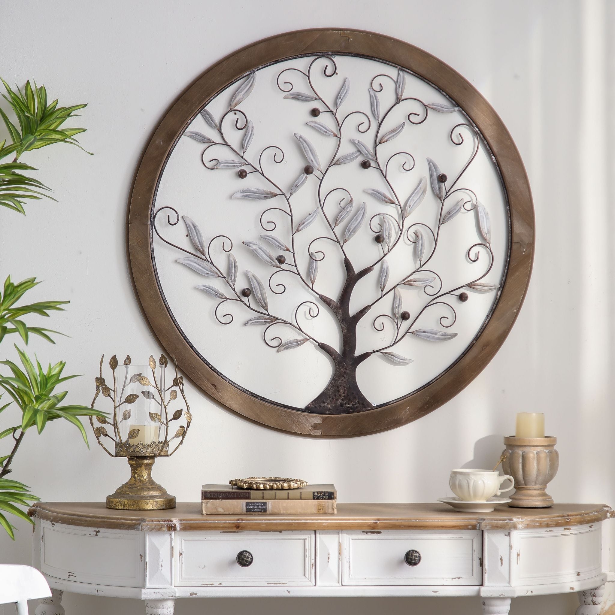 Round tree of life wall art in whitewashed metal and timber, hung above a white French Provincial console