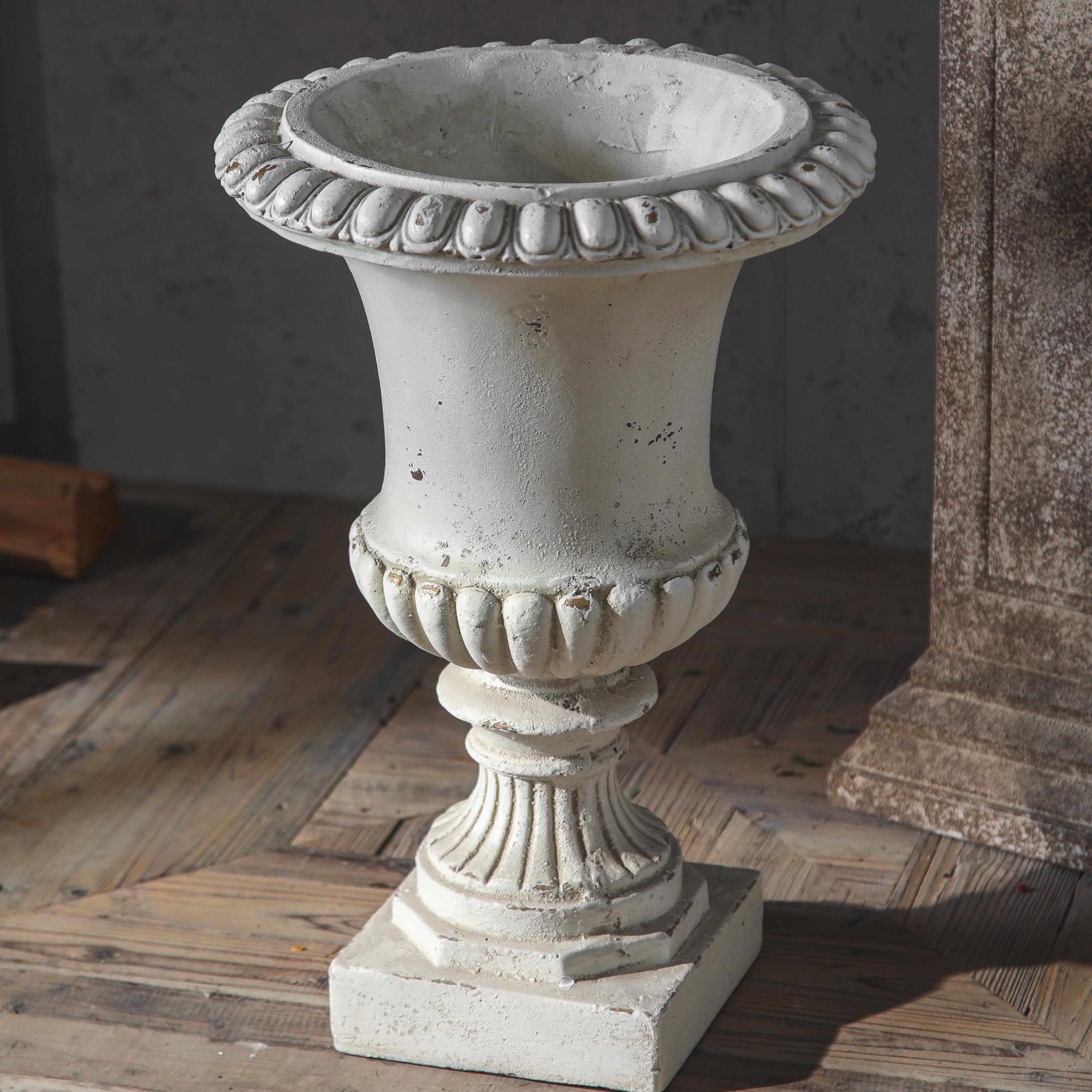 Florentine urn planter front on, gadrooned rim, fluted bowl and square plinth base in antique white.