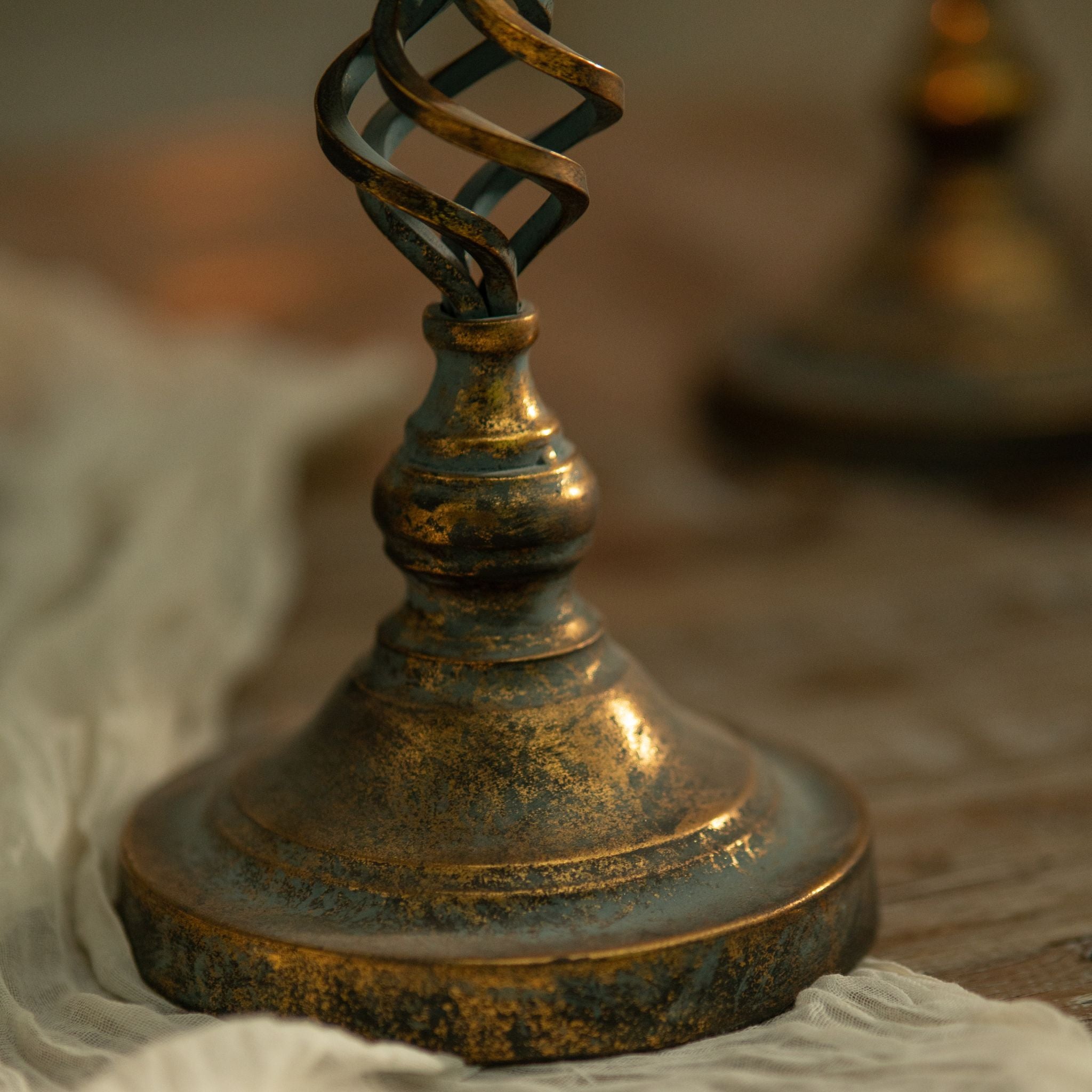 Close-up of the Francis turned baluster foot and stepped round base, showing the antique-gold over verdigris patina.