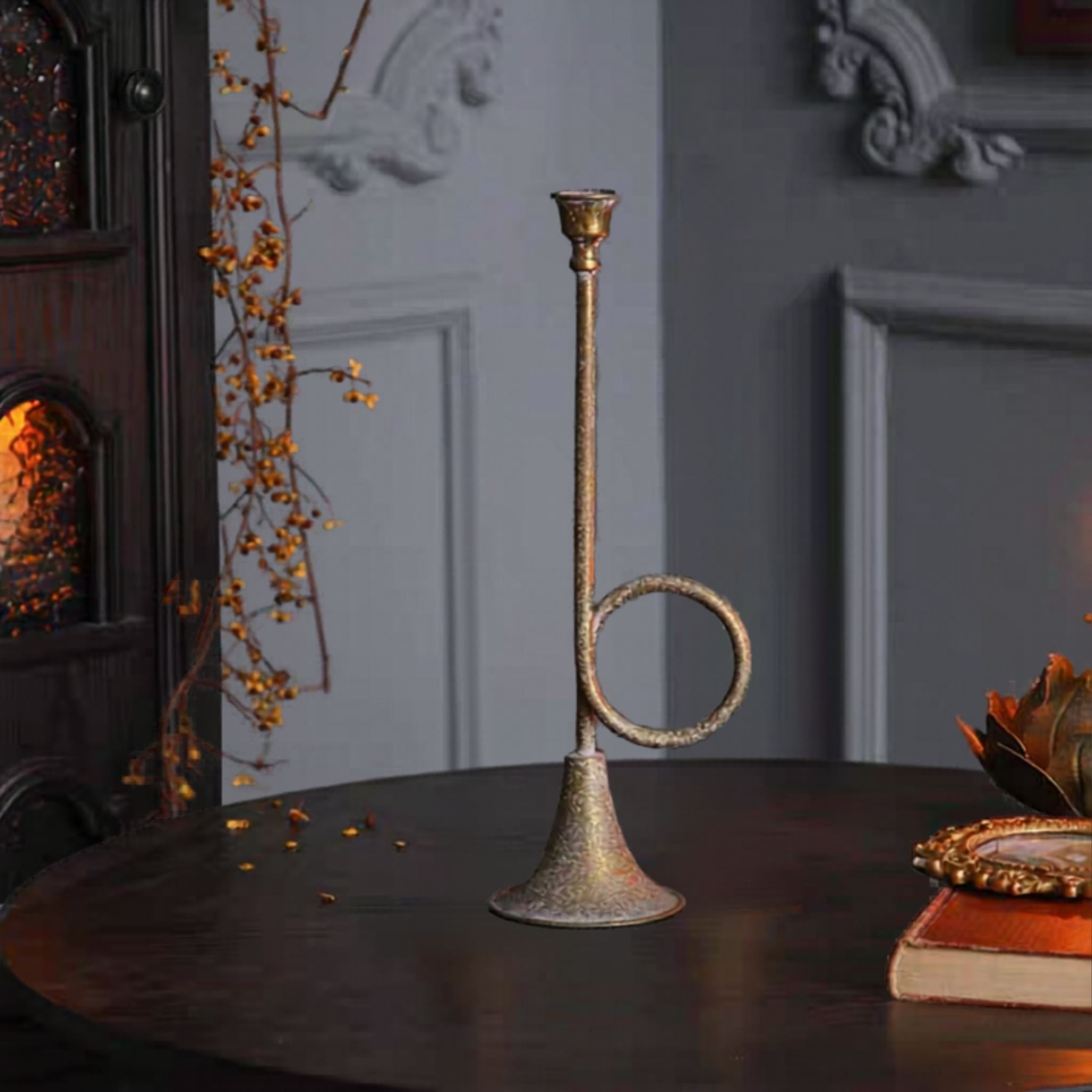 Arnaud tall French provincial horn candle holder in antique gold on a dark table.