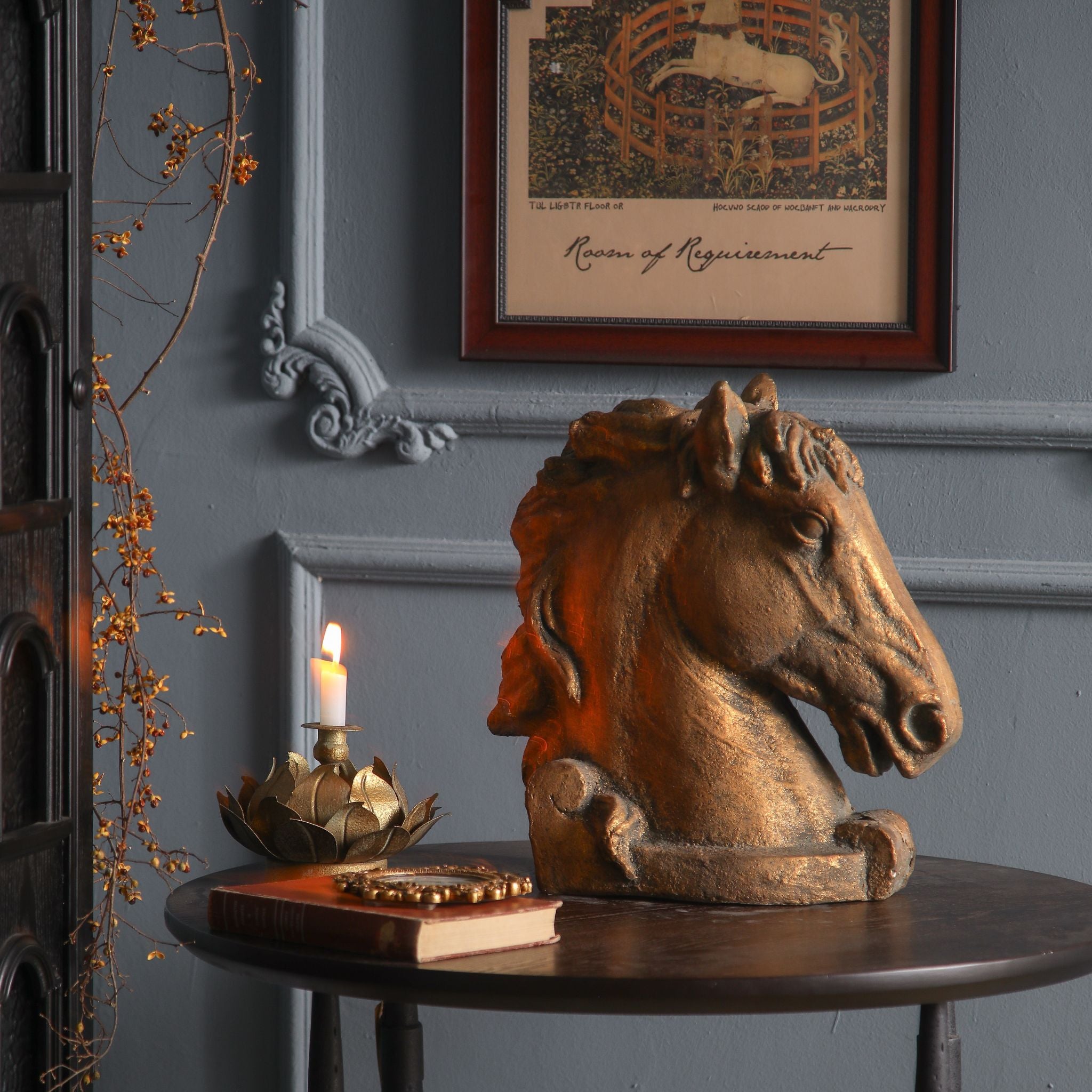 Bayard styled on a round table with candle and books against a grey panelled wall