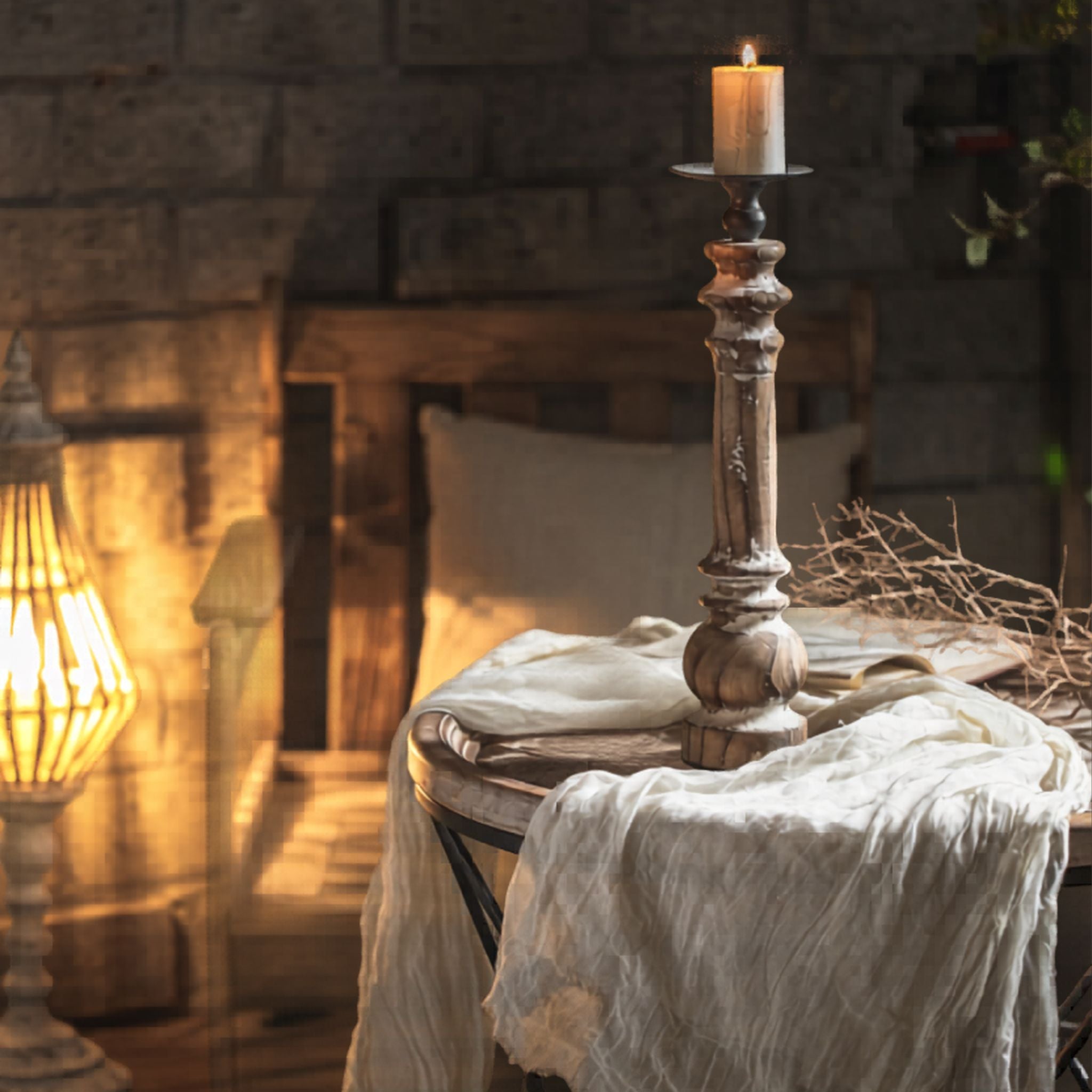 Jacques tall turned-timber pillar candle holder styled on a round table with cheesecloth and dried stems, full height.