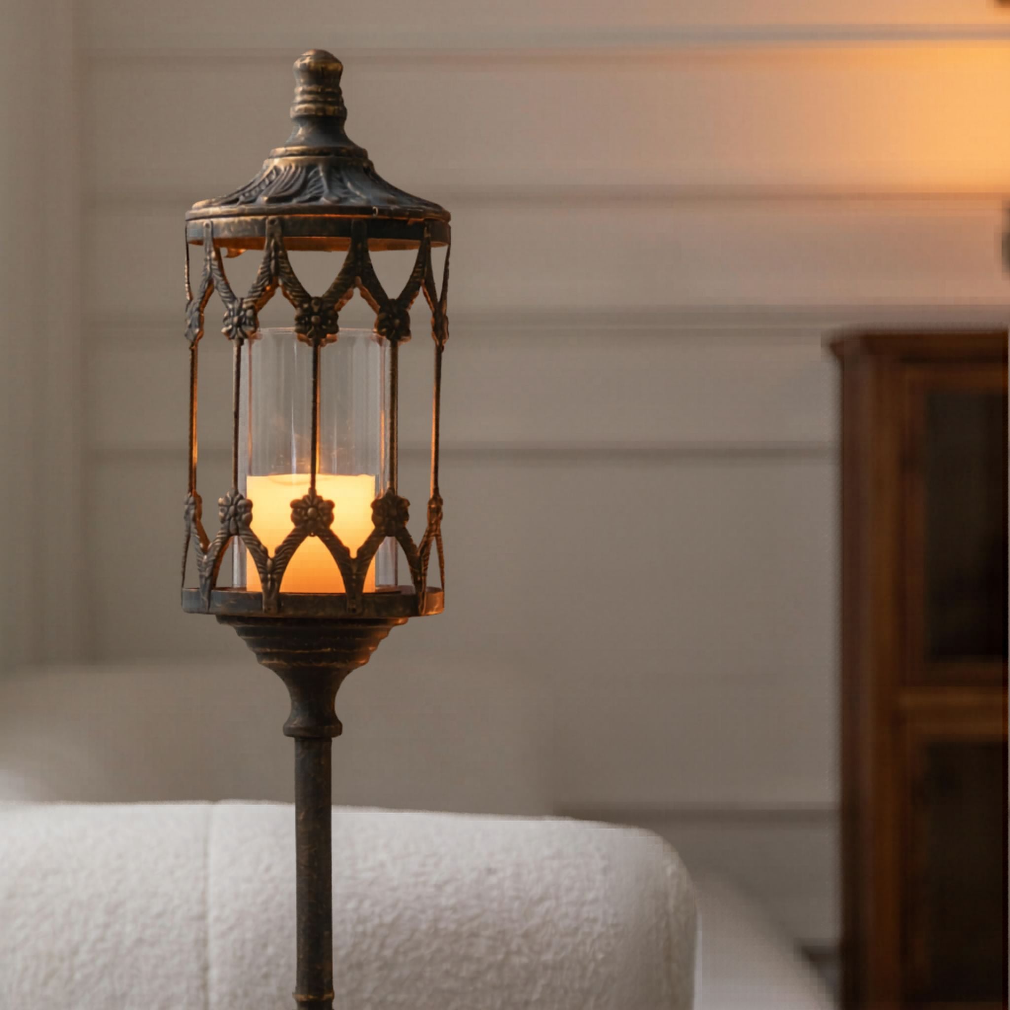 Marc tall aged metal floor candle lantern with a glass hurricane and lit candle