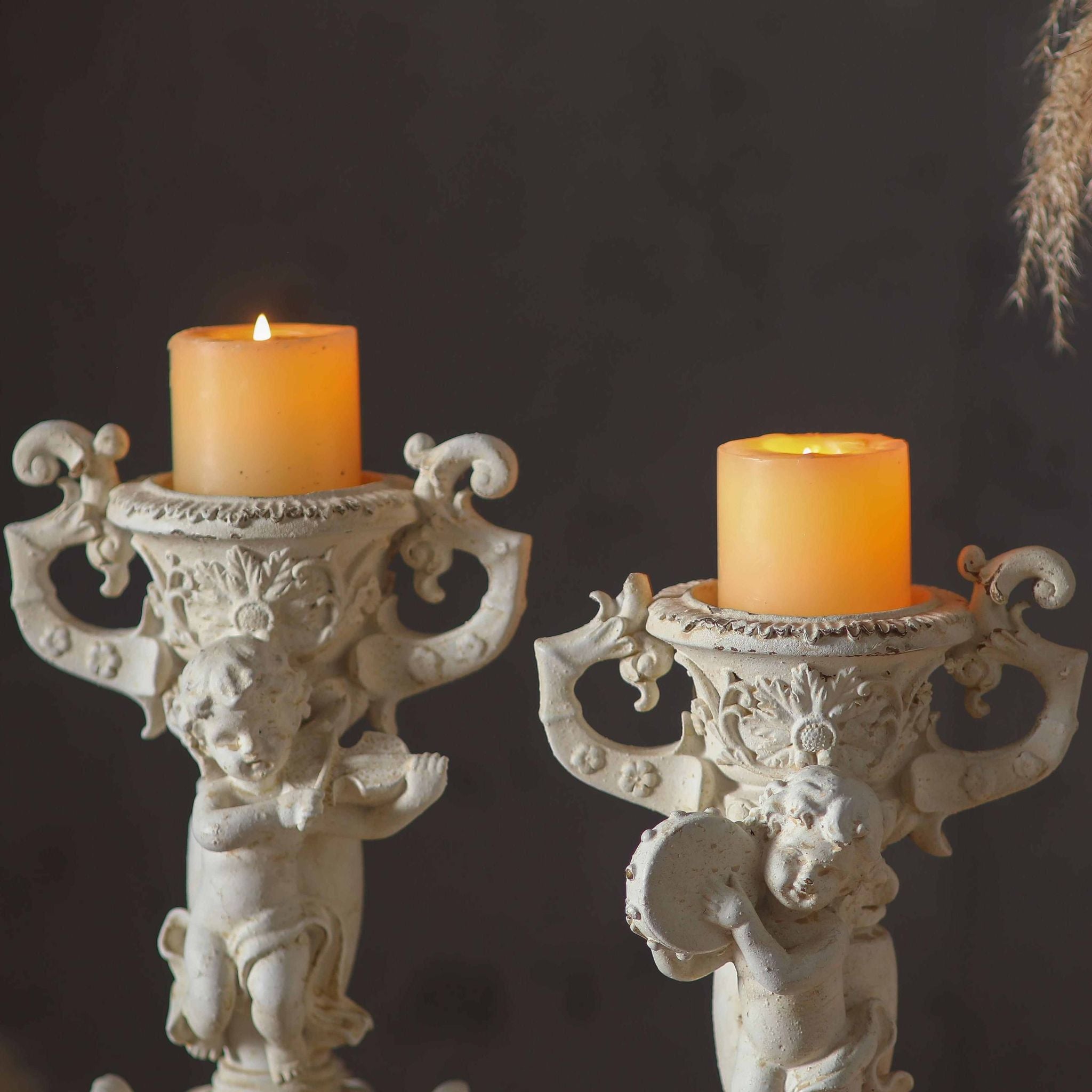 Close-up of the Jean Paul cherub candle holder urn cup and scroll handles holding a lit pillar candle