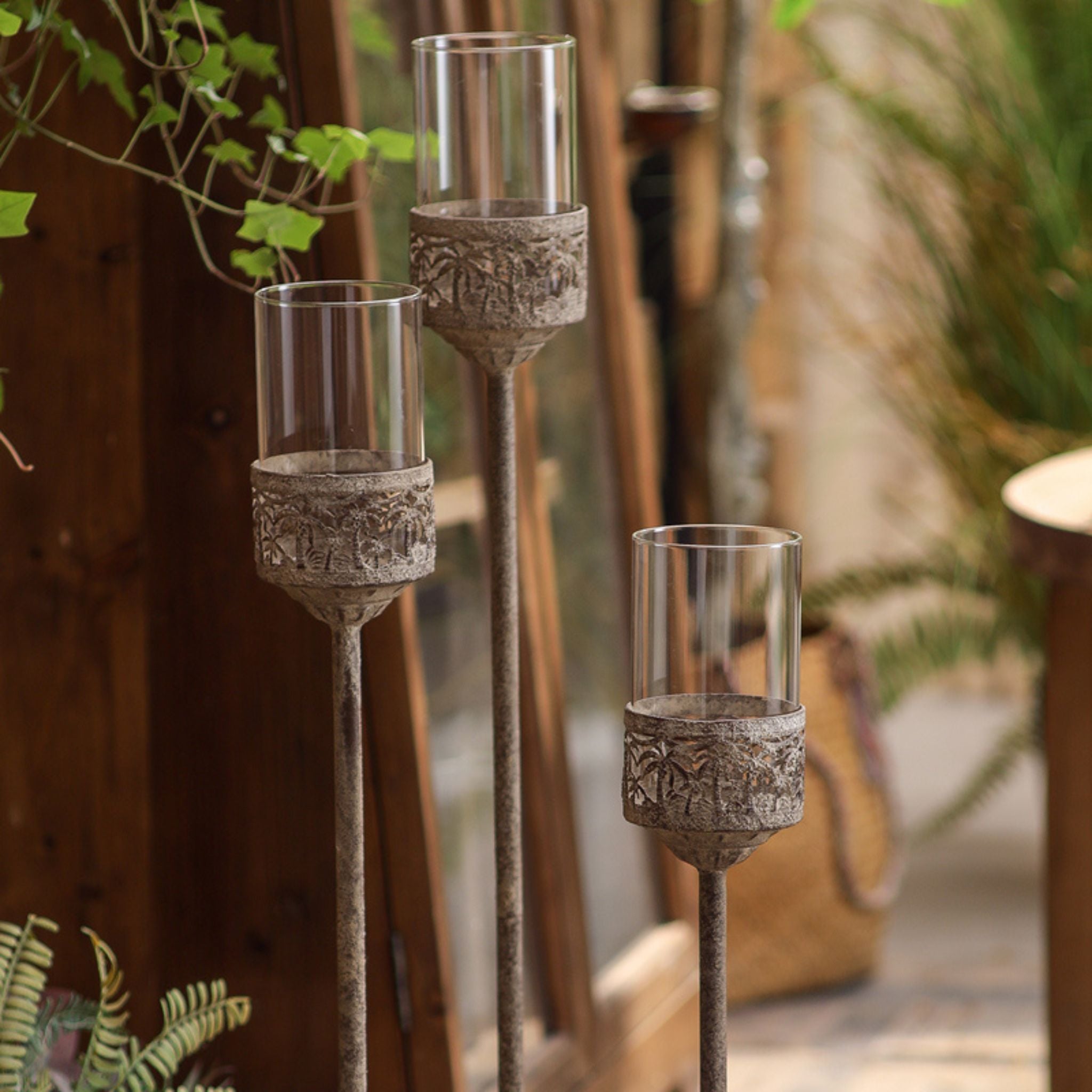 Close-up of three glass hurricane cups and whitewashed openwork bands