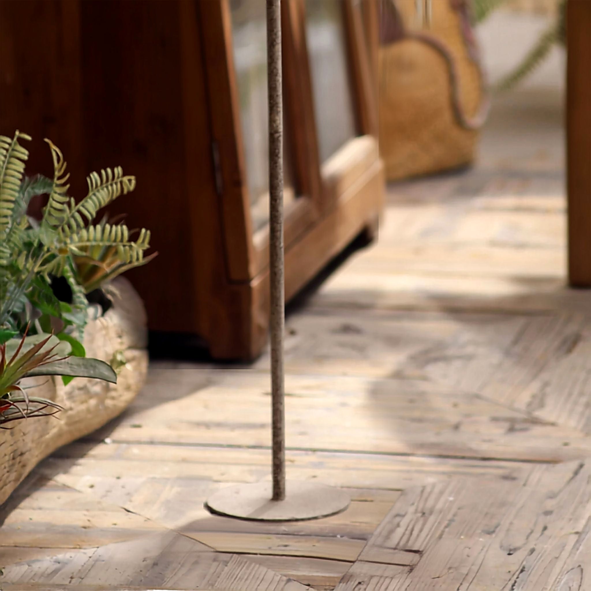 Base detail of the aged metal floor candle holder on timber decking
