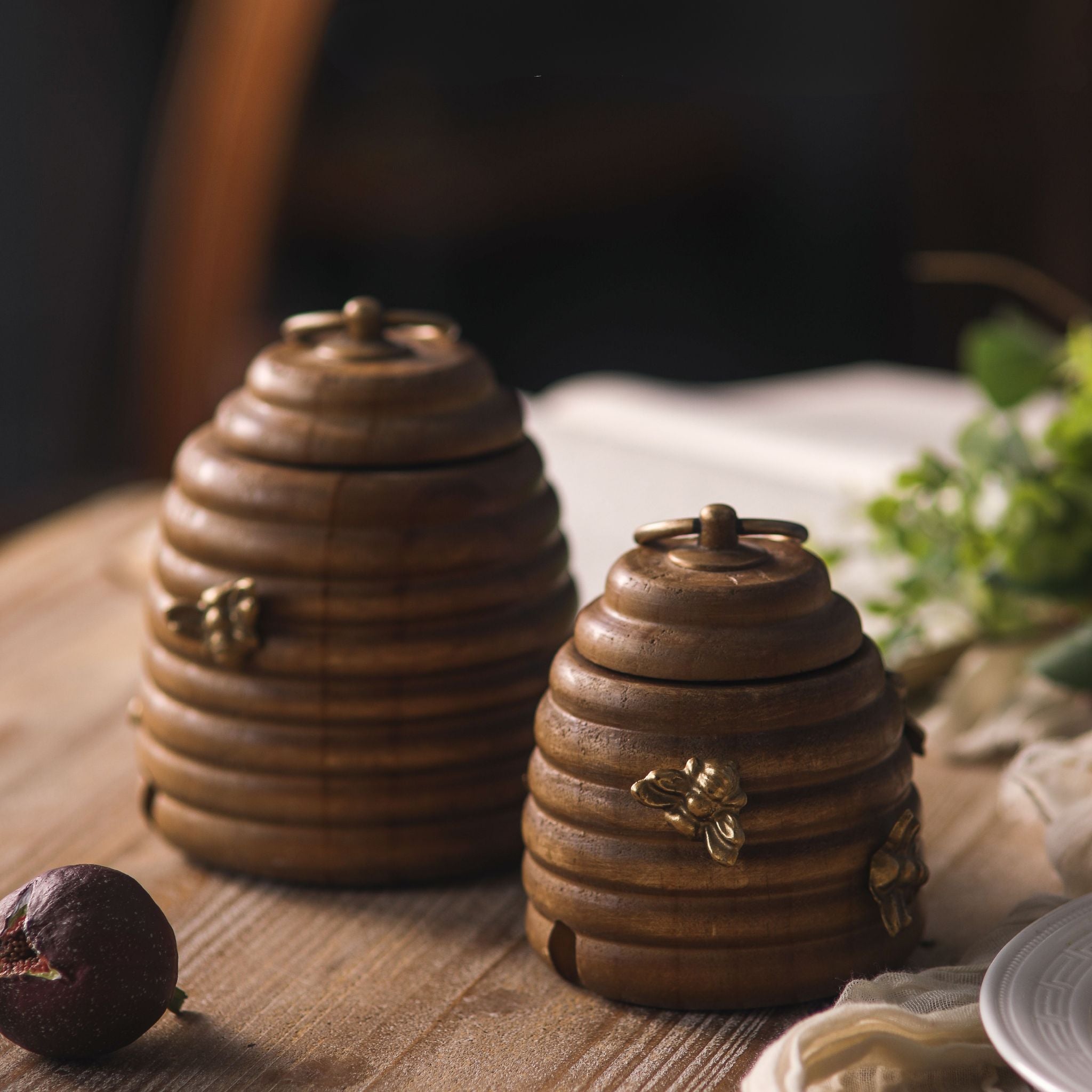 Laure beehive honey pot set of two in pine timber with brass bees and brass ring-pull lids, larger and smaller pots side by side. Hero.