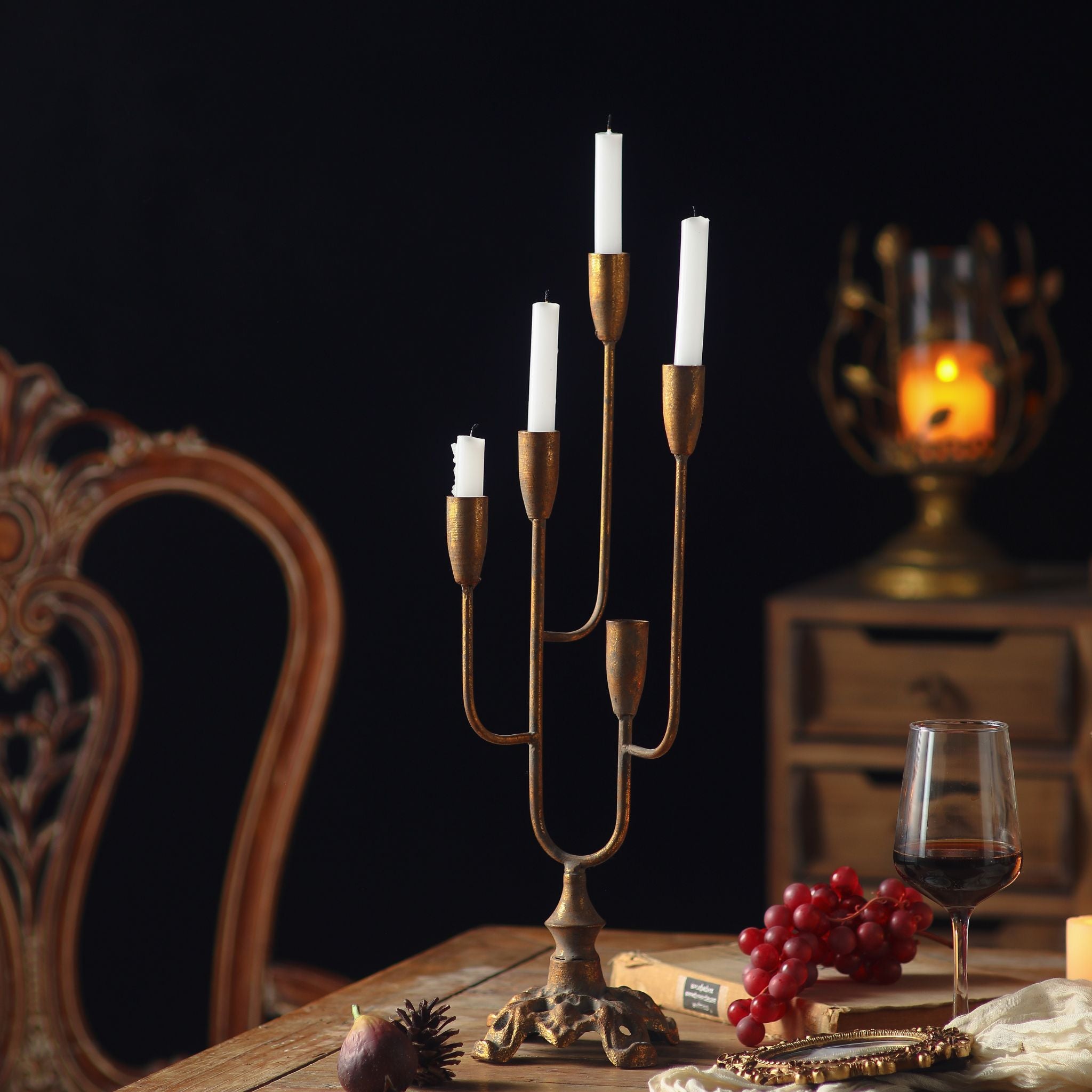 Lisette antique gold candelabra with five graduated arms and white taper candles, styled on a timber table in a French Provincial setting.