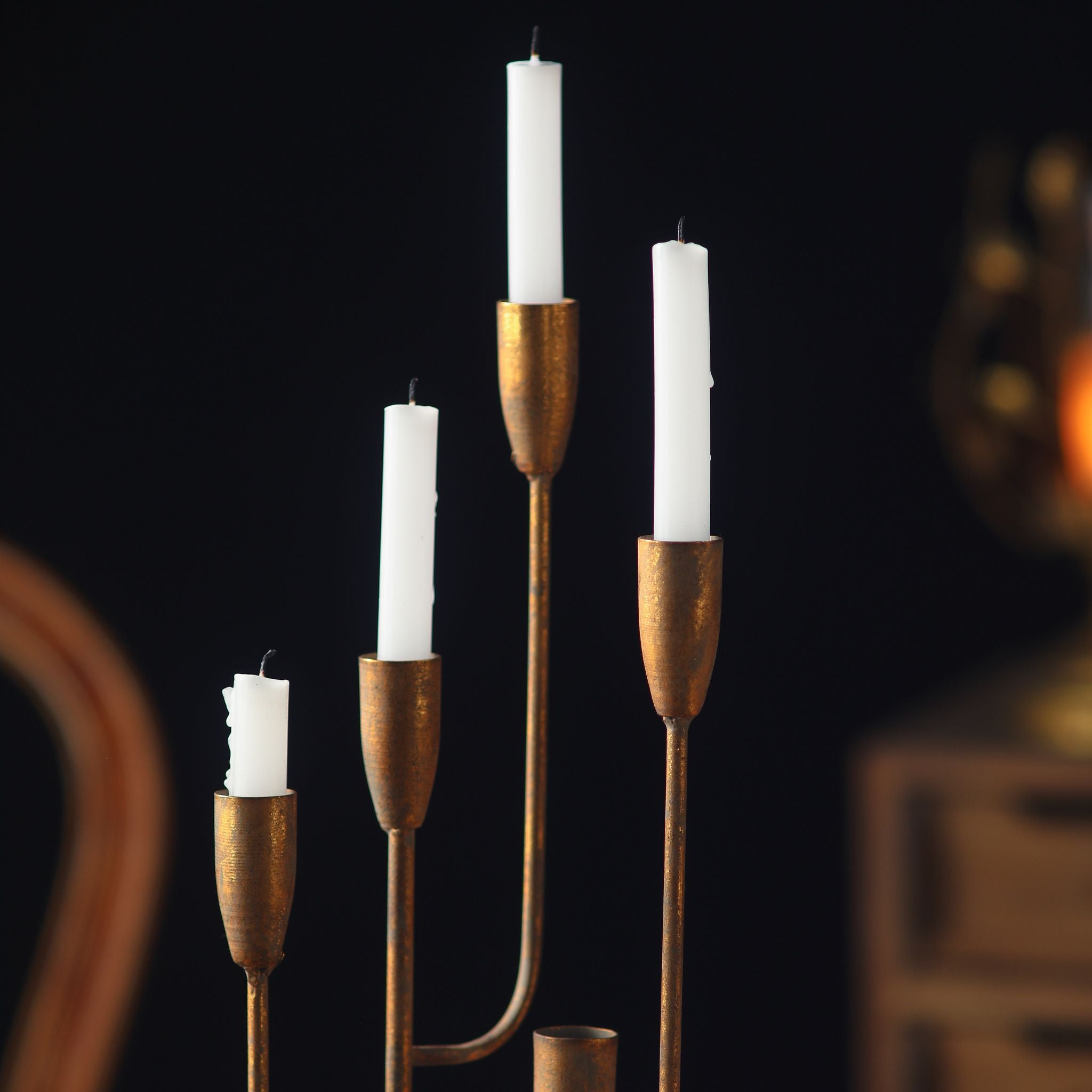 Close detail of the Lisette candelabra candle cups, antique gold aged metal on slim graduated arms, holding white taper candles.