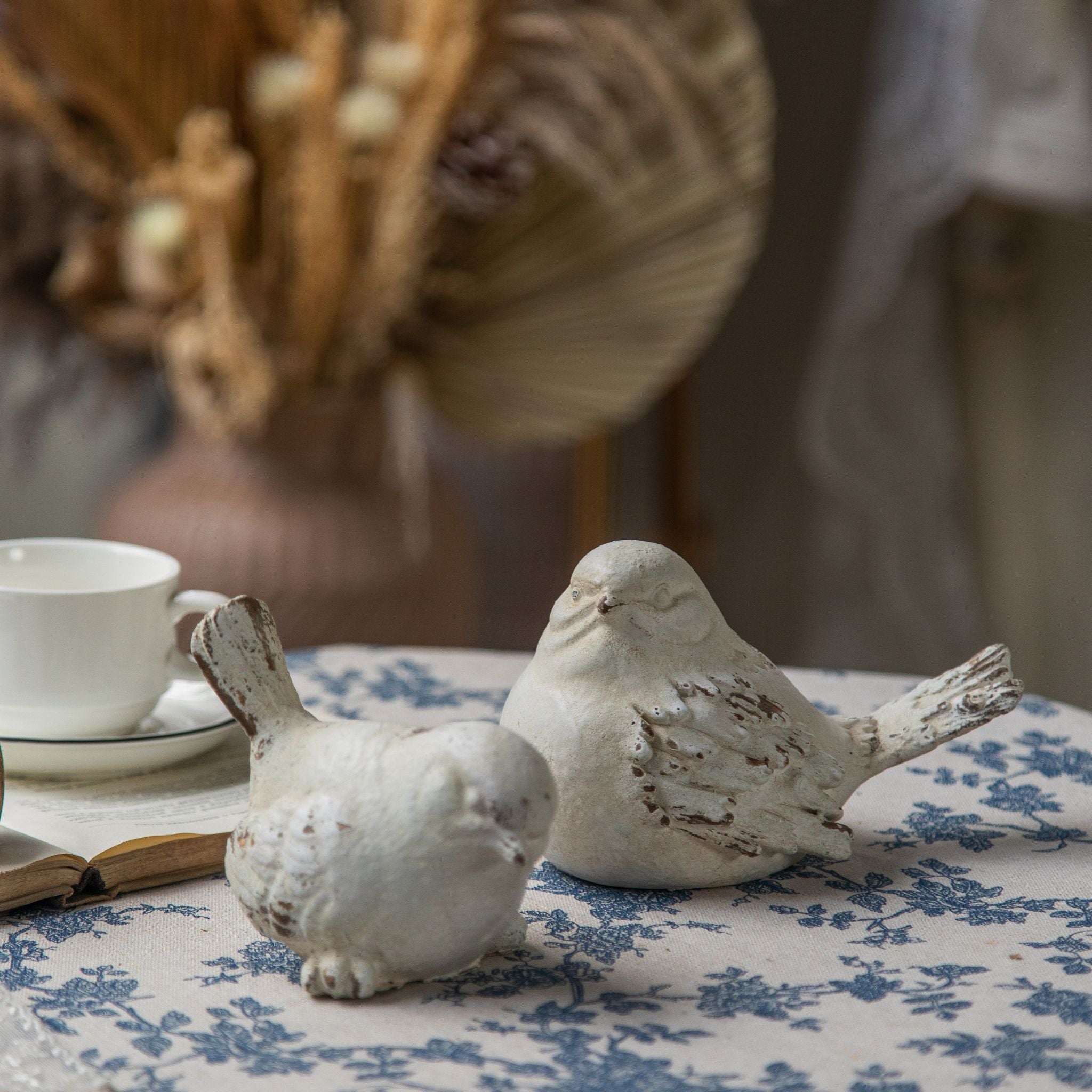 Pair of whitewashed bird figurines in profile, alert and resting poses