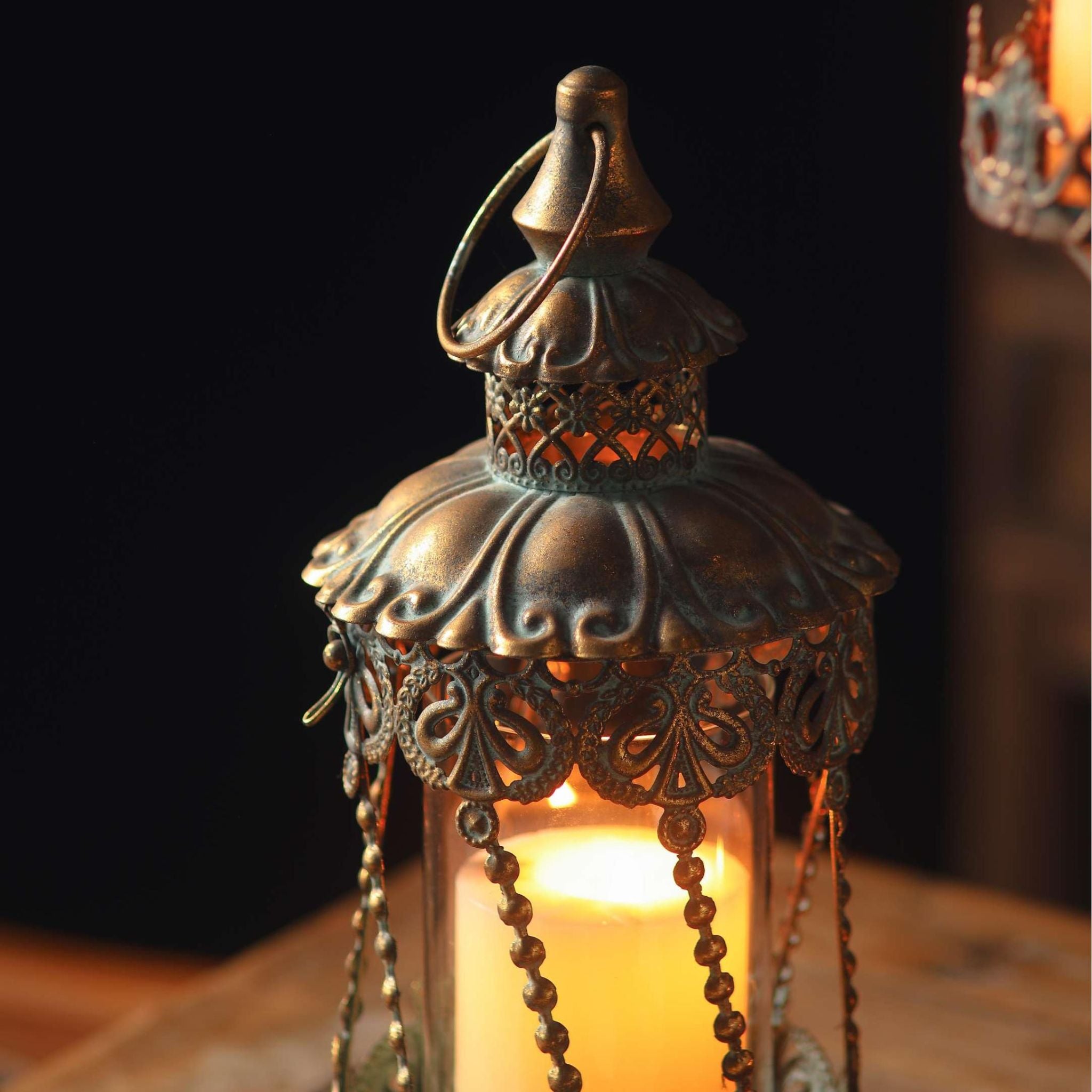 Mael lantern dome lit from within, amber glow through the pierced filigree and embossed antique gold.