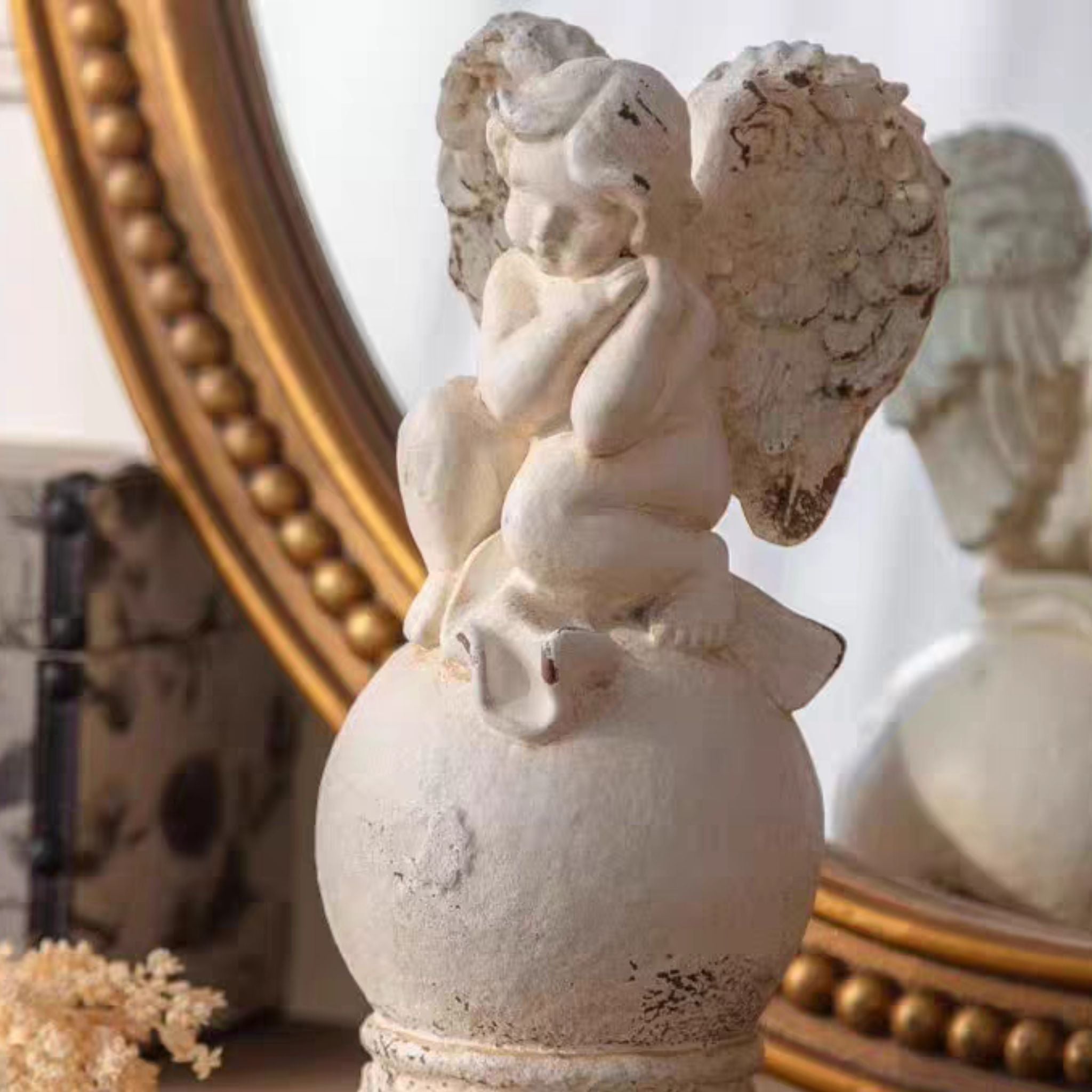 Front view of Mathilde cherub finial on the decorative scrolled pedestal base
