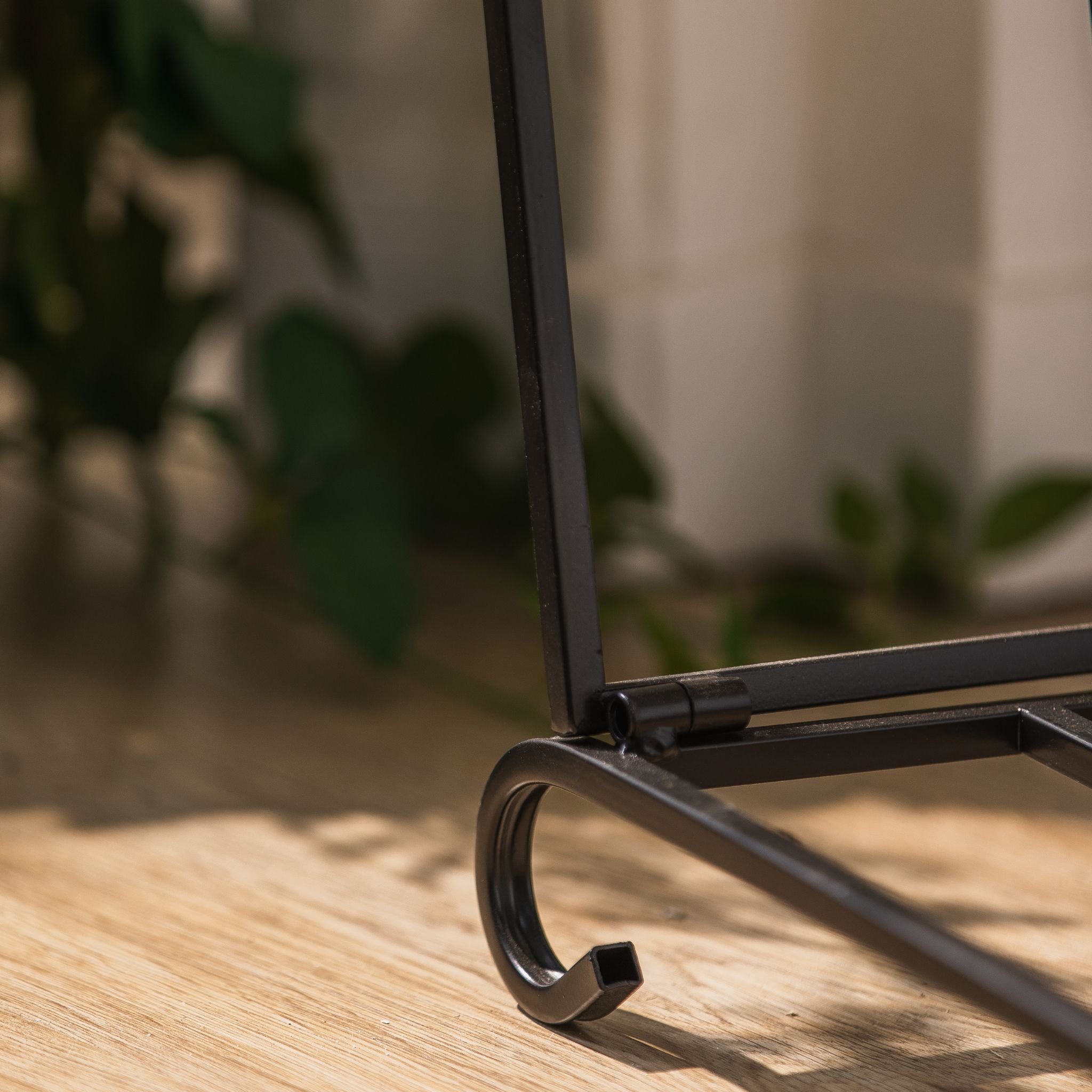 Close-up of the scrolled foot and frame on the Adrien matte black log holder.