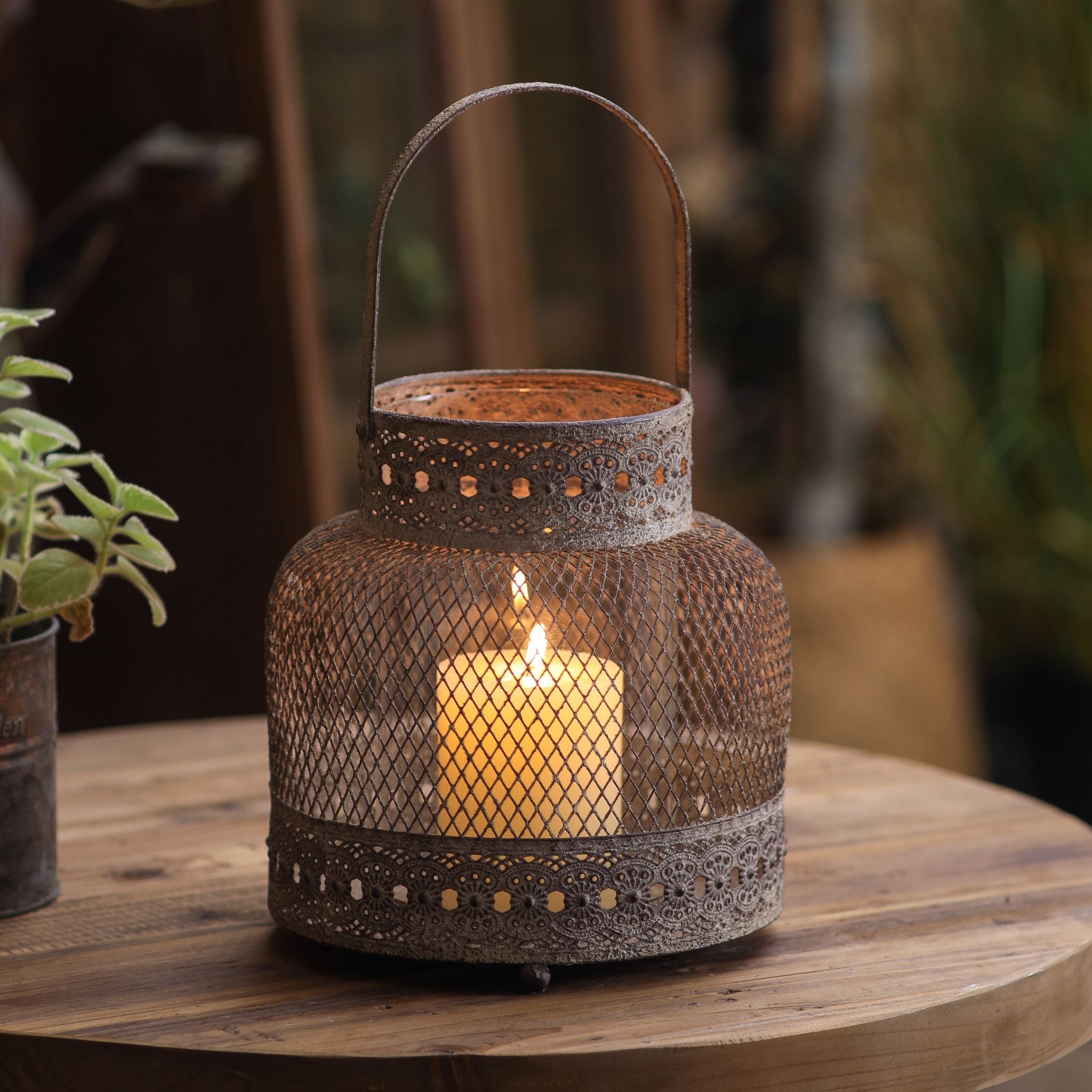 Maurice small weathered metal mesh lantern with a lit candle inside