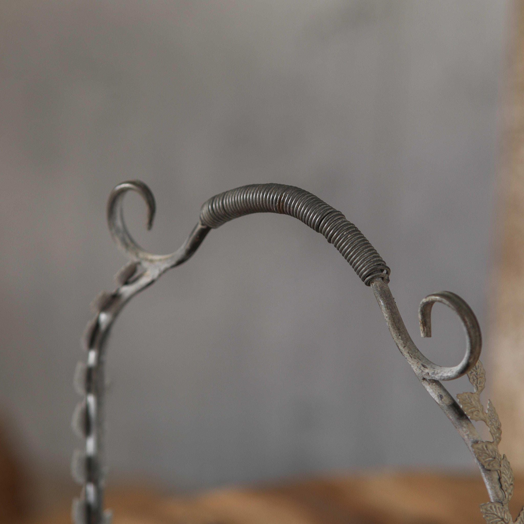 Close-up of the Meline basket arched handle with scrolled ends, wire grip, and leaf detail.