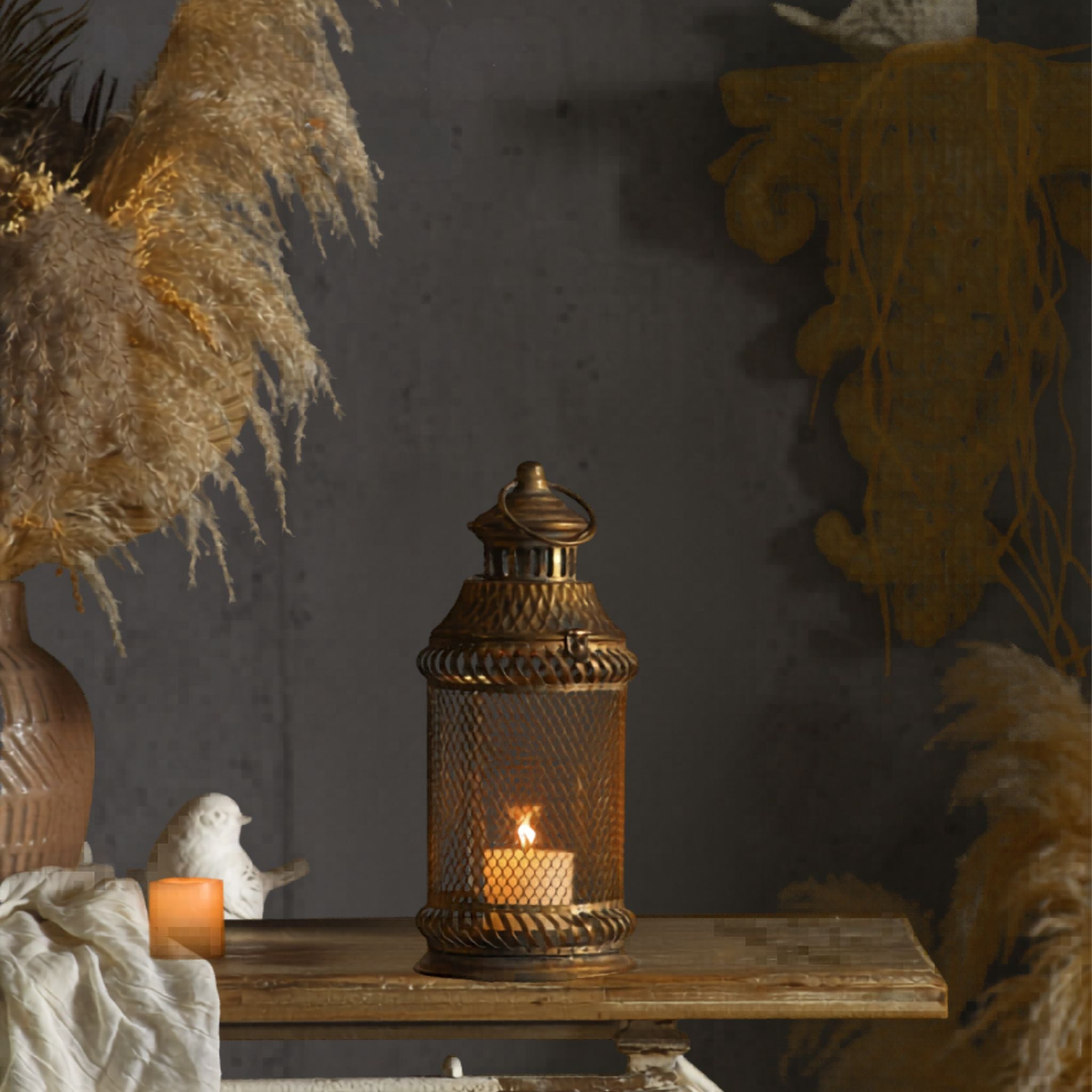 Melissa antique gold mesh lantern with a lit candle, styled on a table
