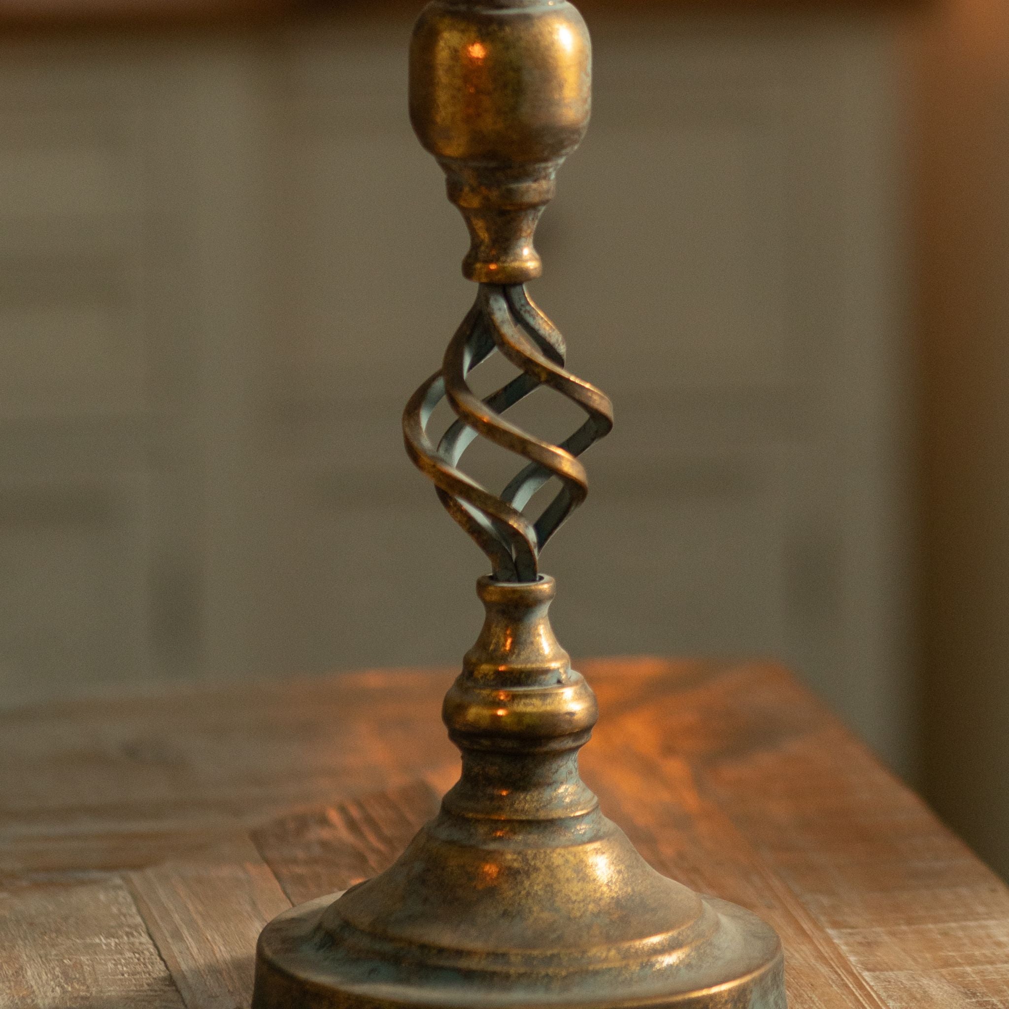 Close-up of the Michel twisted open-cage stem with turned ball knop and baluster foot, showing the antique-gold over verdigris patina.