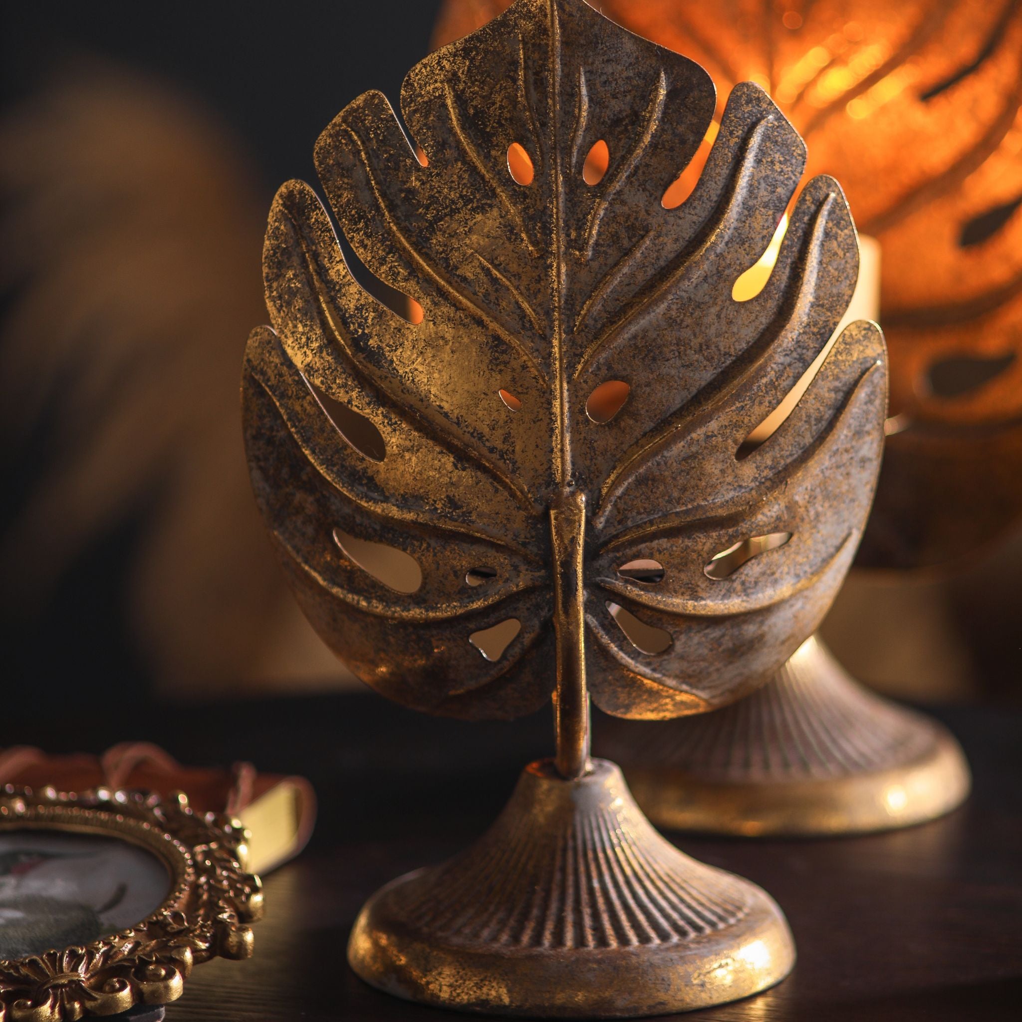 Rear view of the pierced monstera leaf and fluted pedestal base in aged metal with antique gold.