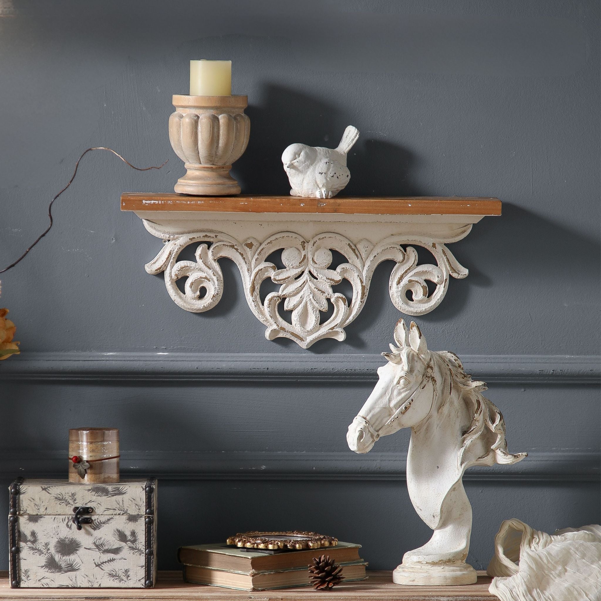 Natalie French Provincial mantel shelf in distressed whitewash with pierced openwork scroll apron and timber top, styled on a charcoal wall with a candle holder and small white bird. Hero