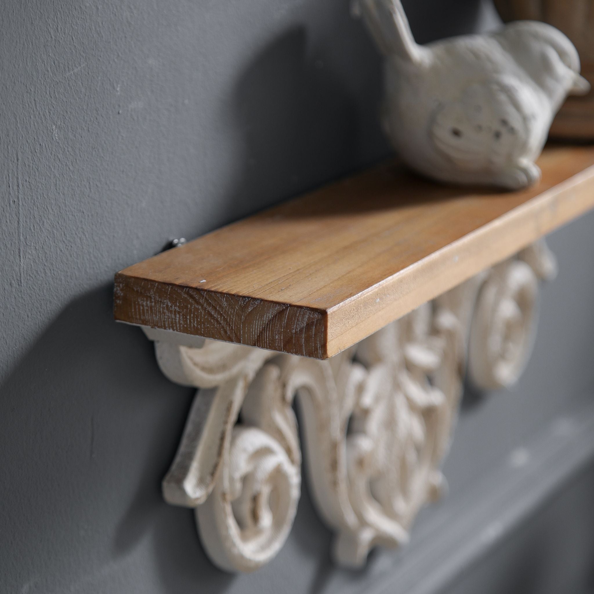 Close-up of Natalie mantel shelf showing the warm fir wood top edge and the carved openwork scrolls beneath