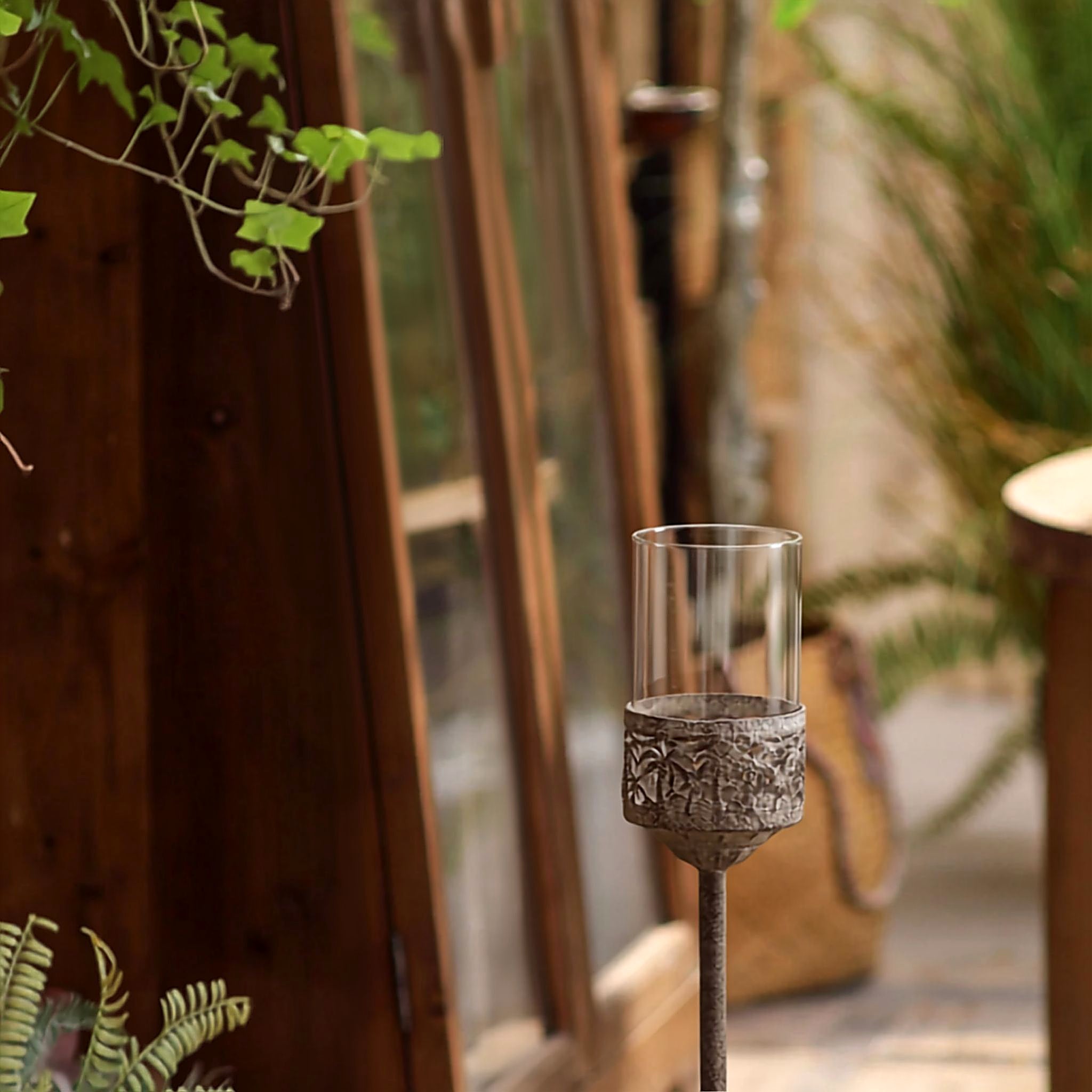 Octave floor candle holder standing on a timber verandah beside a doorway