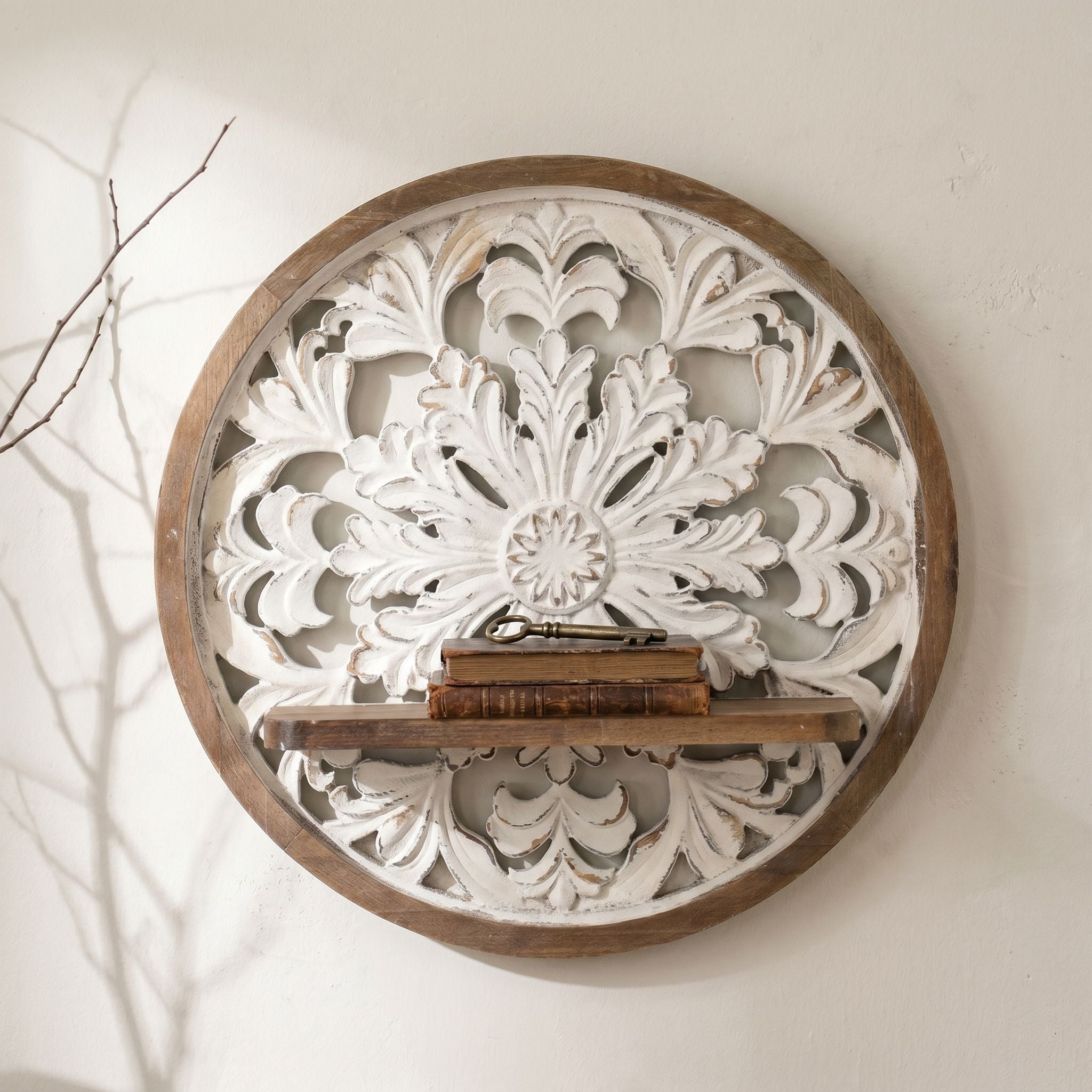 Olive round wall medallion shown front on, full whitewashed acanthus relief and central rosette, timber shelf with antique books and a brass key