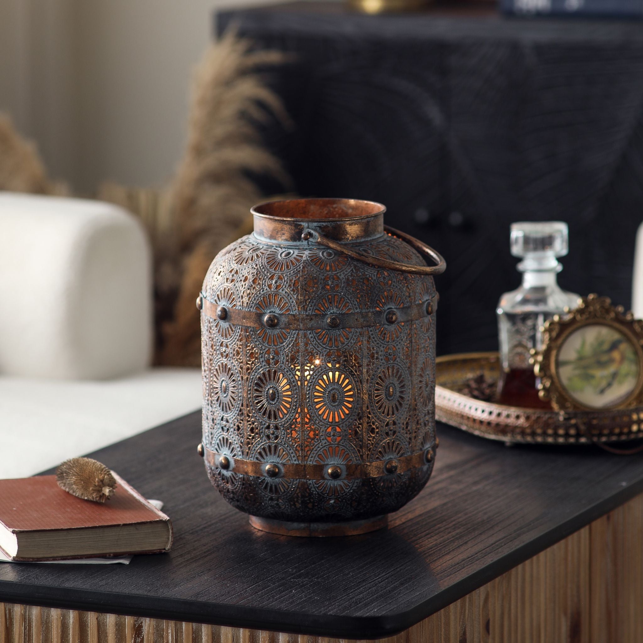 Aicha lantern lit on a side table beside a decanter and tray