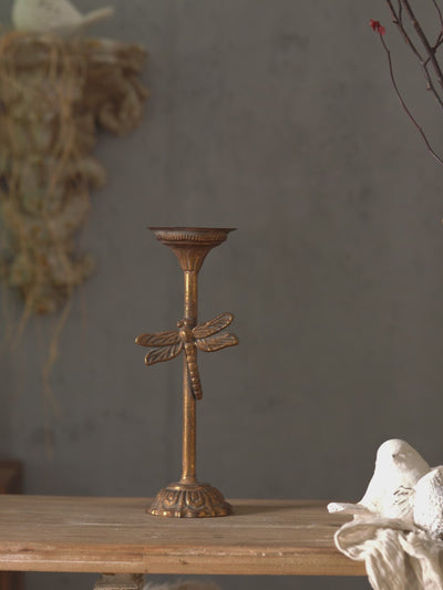 Video of the Lara dragonfly candlestick set, two aged gold metal candle holders lit with pillar candles