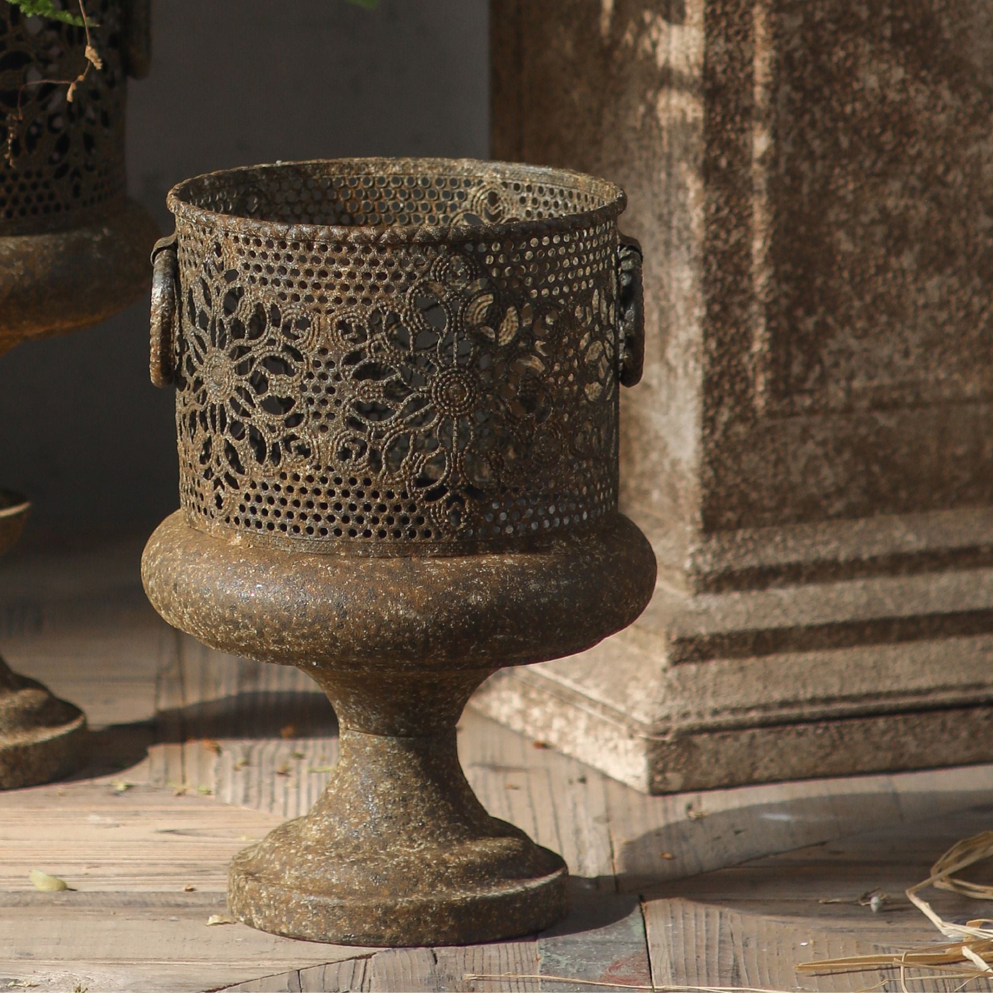 Raoul aged metal pierced pedestal planter with floral cutwork, front on. Hero.