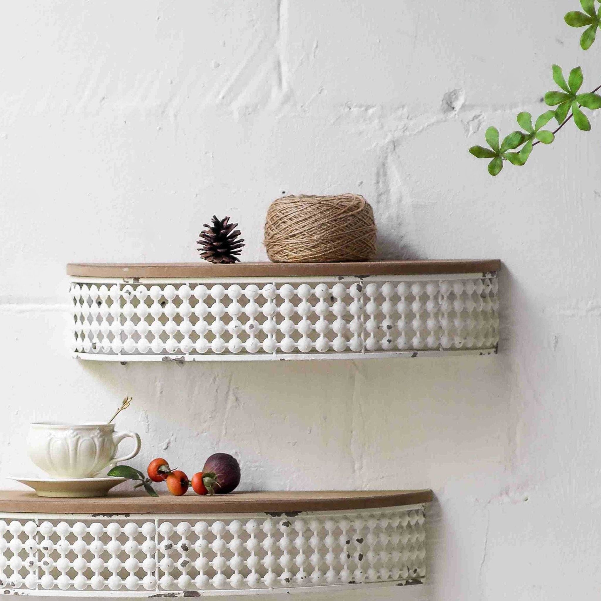 Rita French Provincial half moon wall shelf, the smaller size, mounted on a white brick wall with a distressed white openwork metal gallery and fir timber top, styled with a pinecone and jute twine. Hero.
