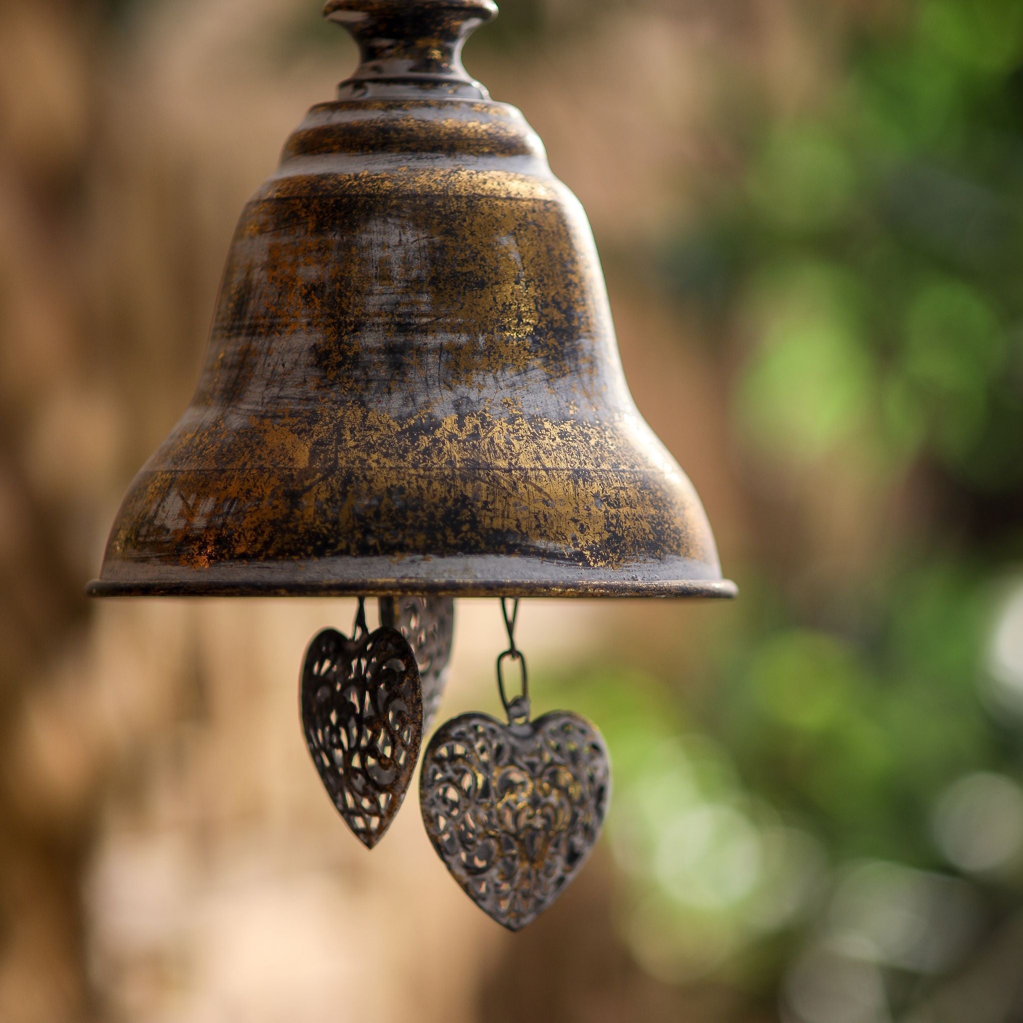 Rochelle hanging bell close-up showing the distressed antique gold finish and the pierced filigree hearts beneath the rim.