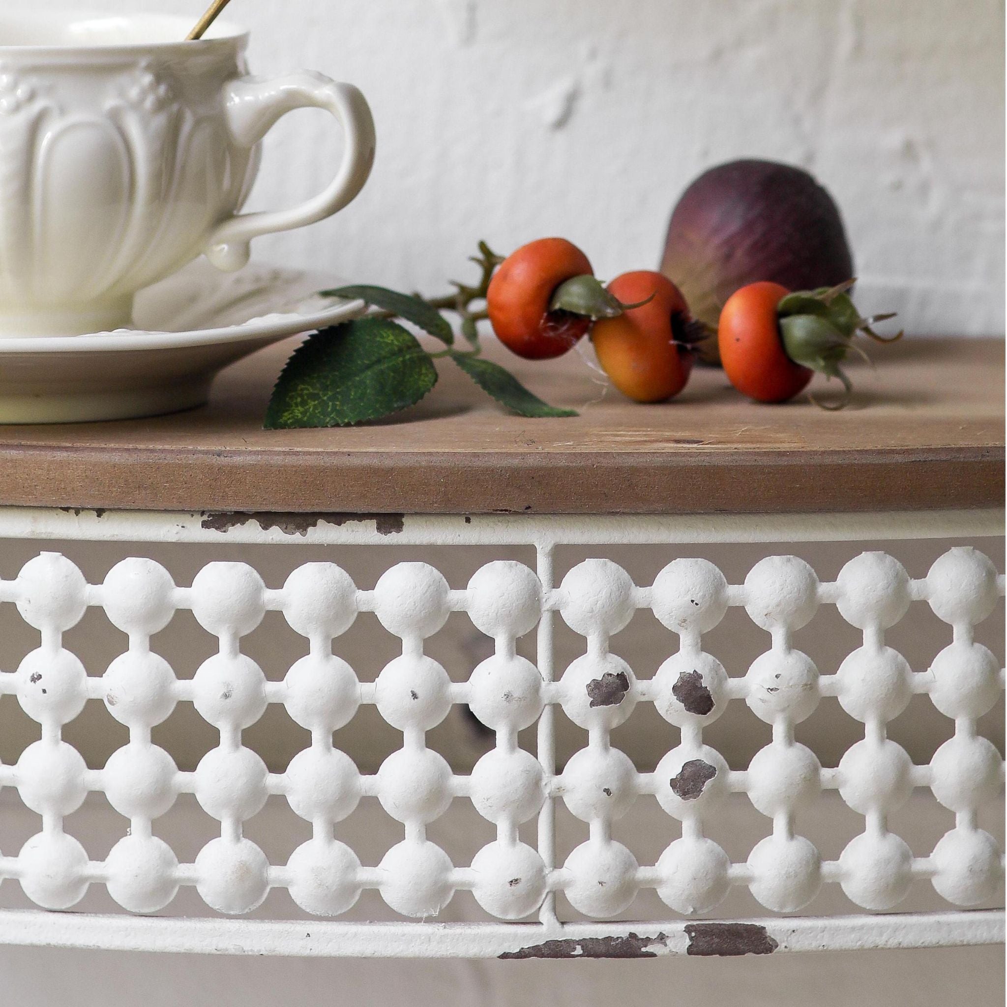 Rolande wall shelf detail, distressed white openwork ball-and-bar metal gallery worn back to the bare metal, with the fir timber top edge