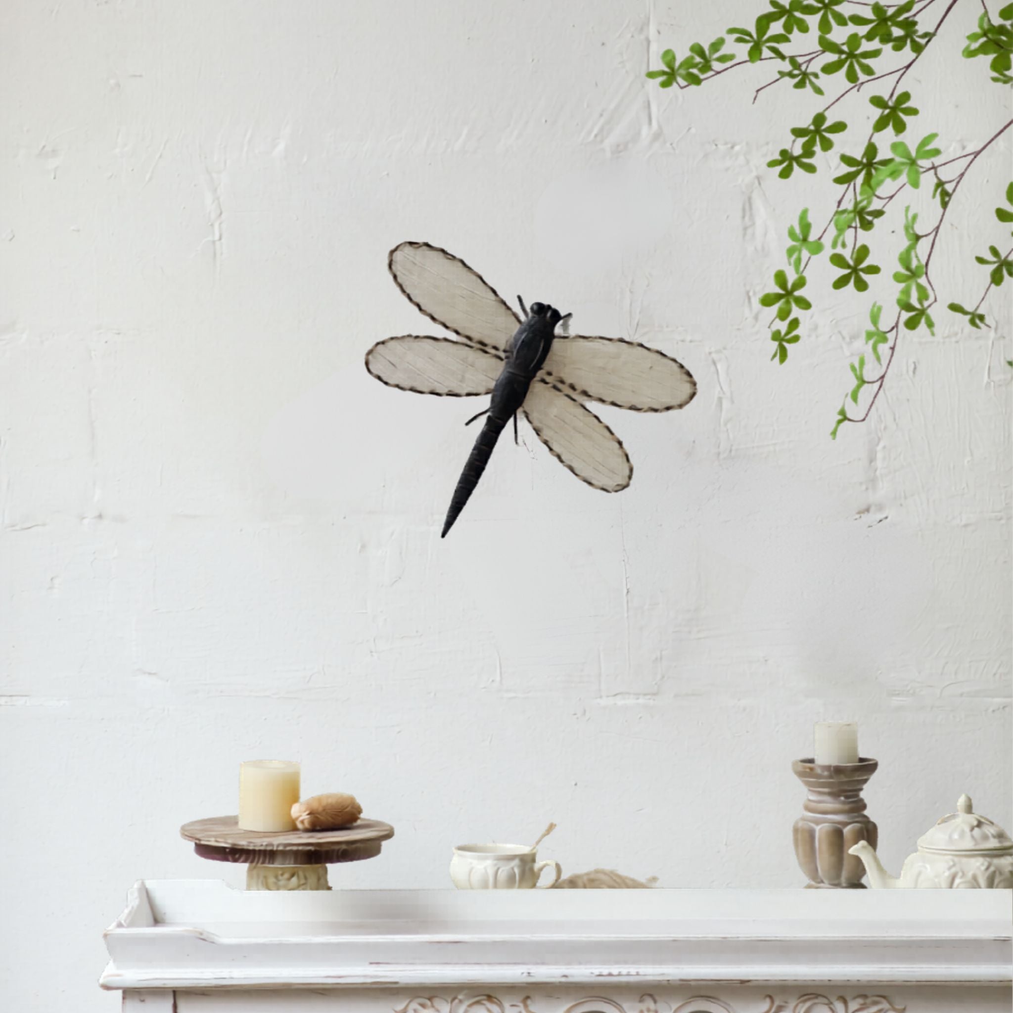 Aged dark metal dragonfly wall art with woven jute wings, hung above a white French Provincial console
