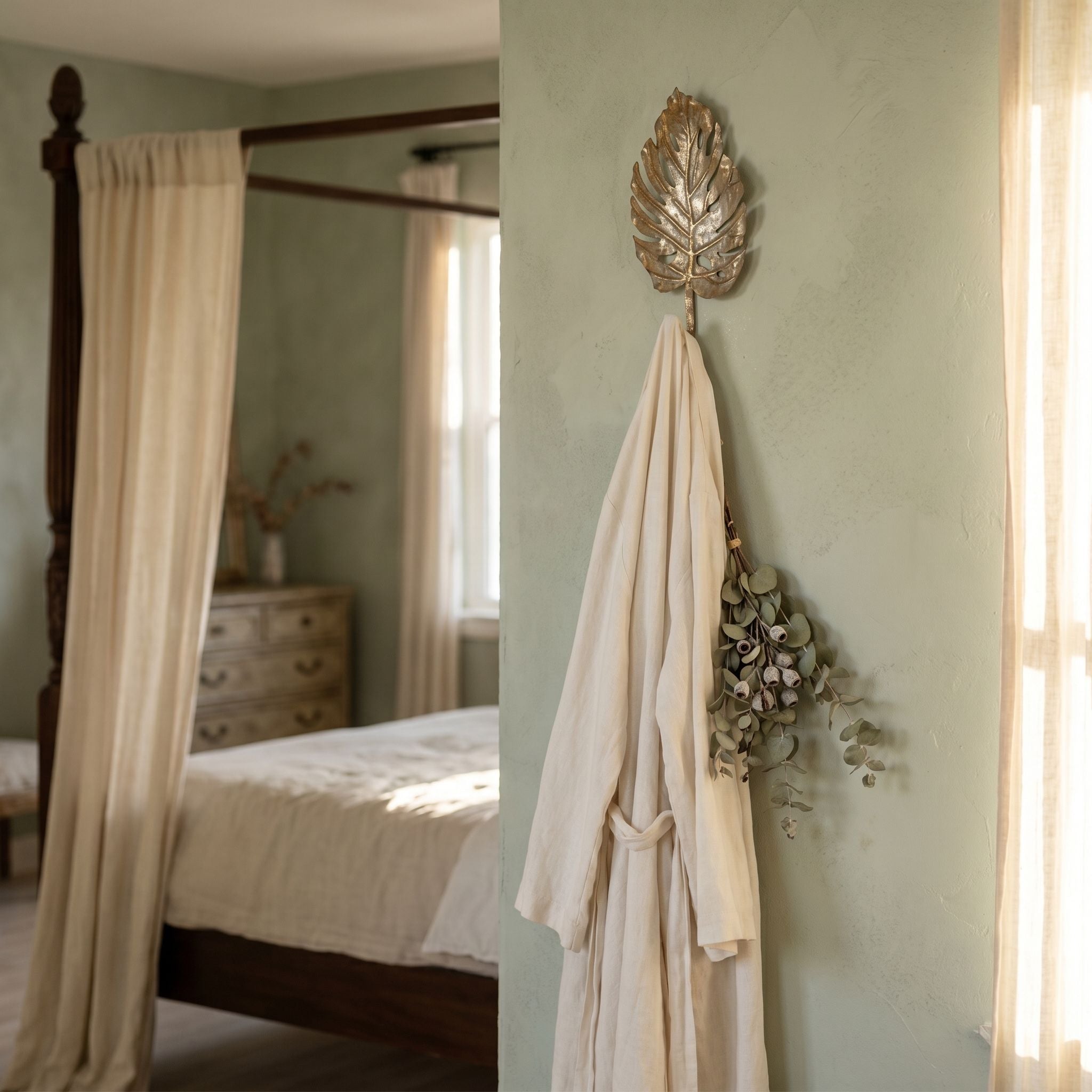 Roxane leaf wall hook on a sage wall holding a draped linen robe and a bunch of dried eucalyptus