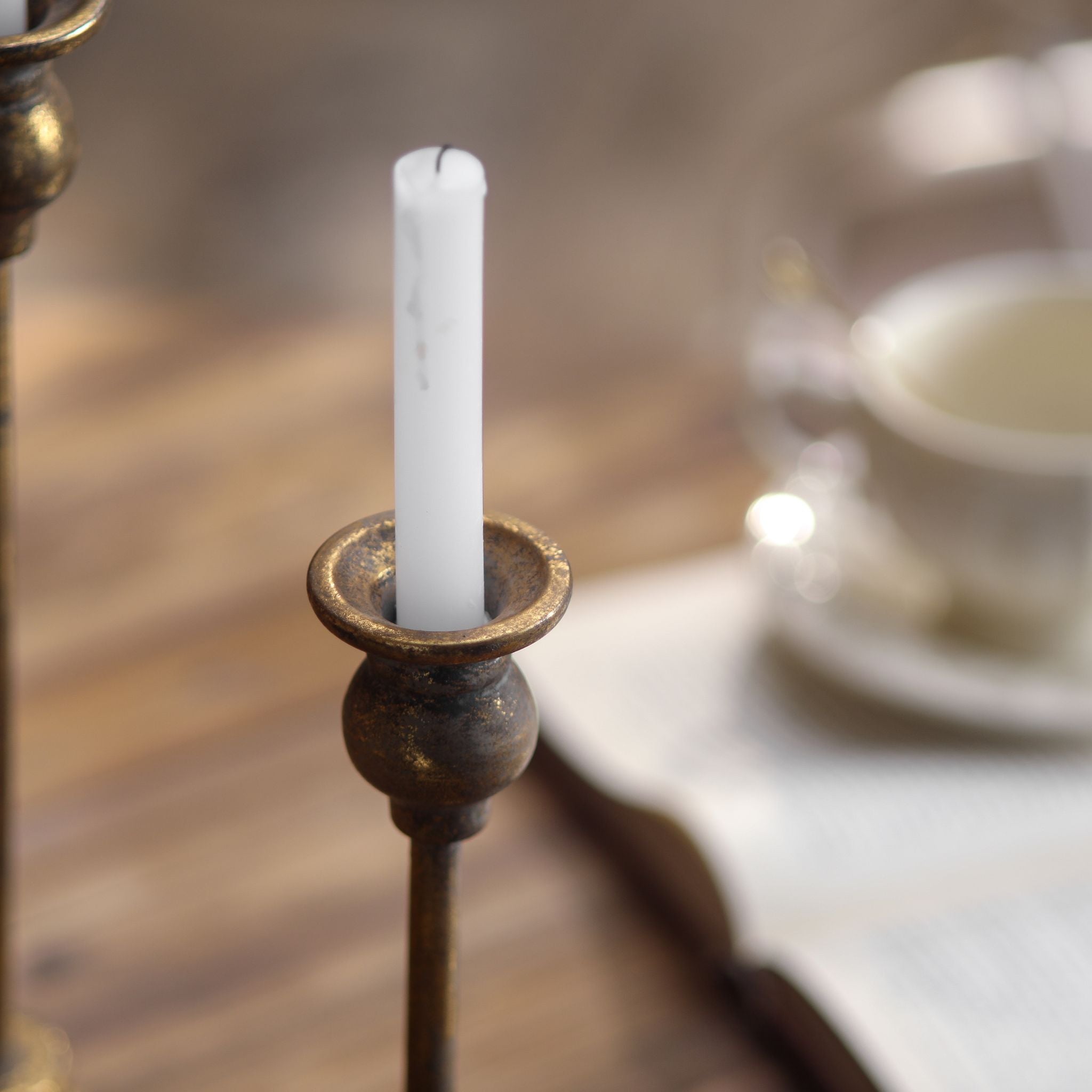 Single Karine taper candlestick cup holding a white dinner candle