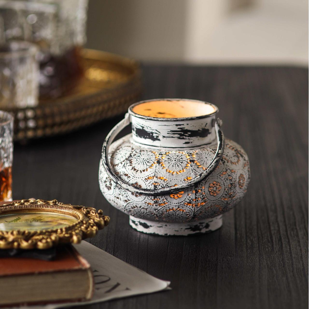 Soraya lantern styled on dark wood beside brass tray and antique gilt frame, warm candlelit interior scene