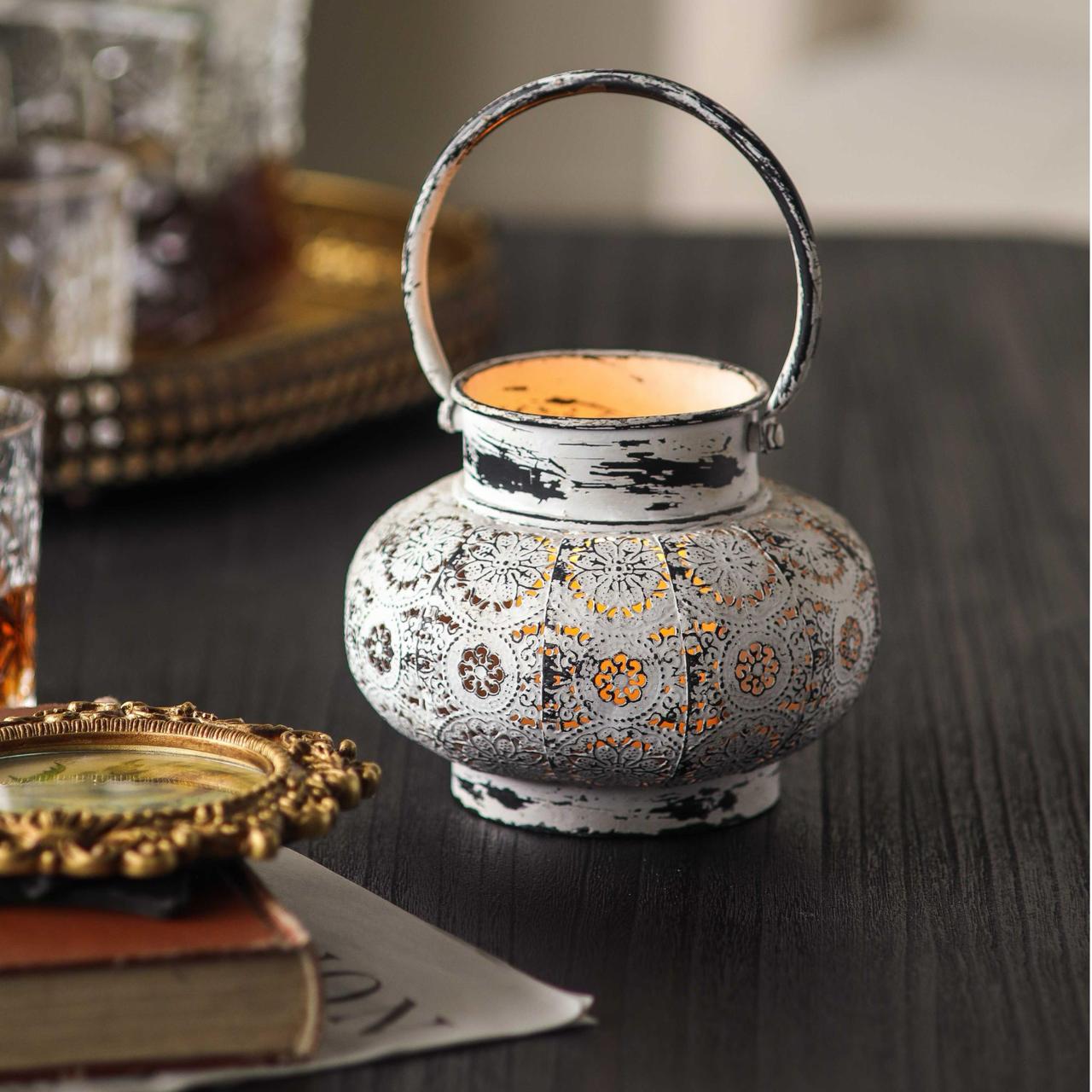 Soraya distressed white lantern with looped handle raised, lit tea light glowing through pierced floral cut-outs
