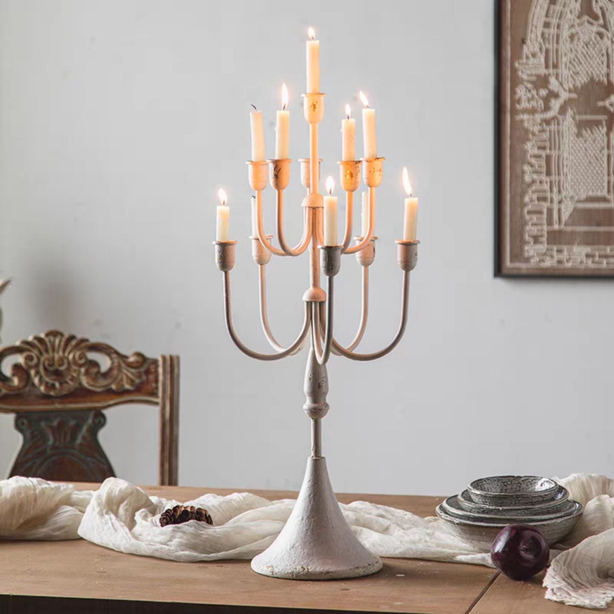 Marjorie distressed cream tiered candelabra lit with taper candles on a trumpet base. Hero.