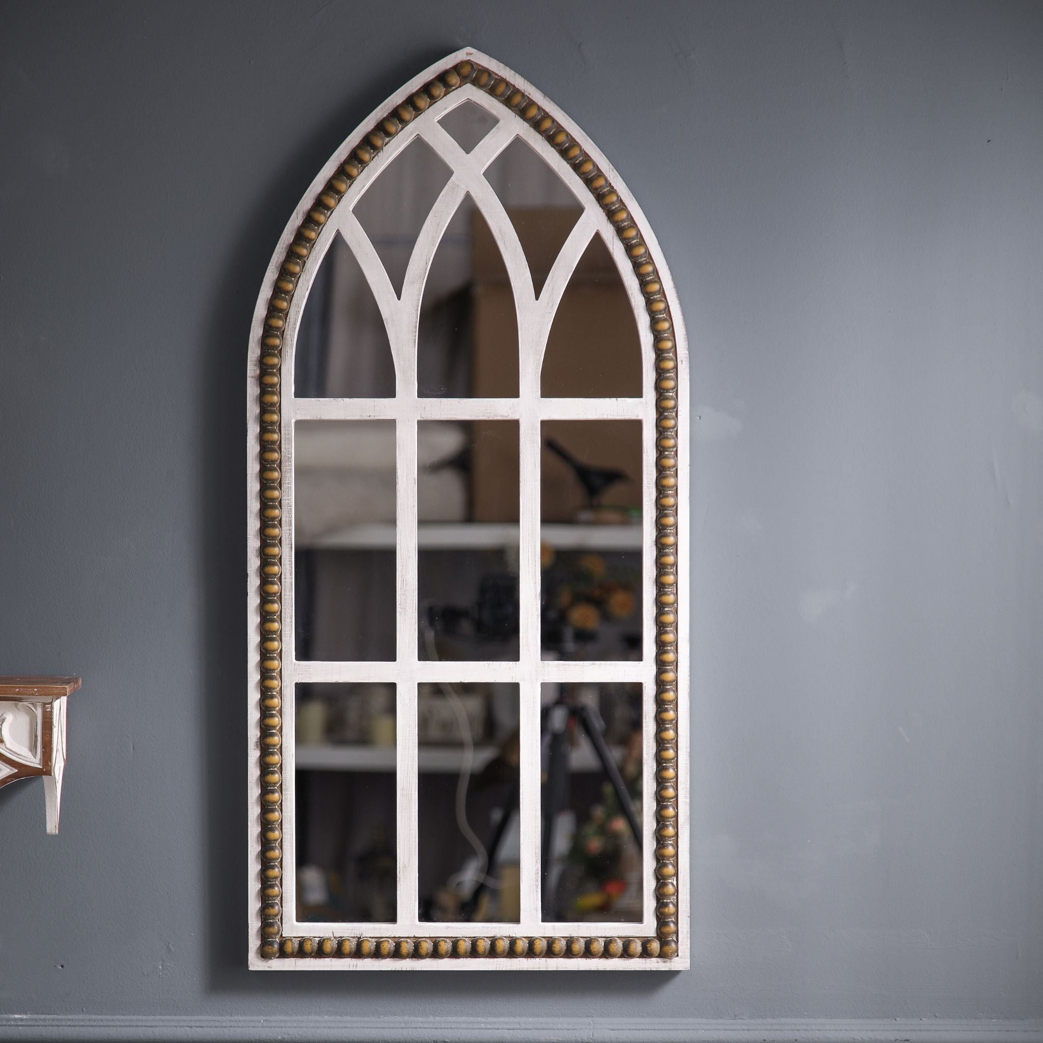 Vincent French Provincial Gothic arch window mirror with whitewashed fir frame and bronze-gilt beaded trim, hung on a grey wall. 
