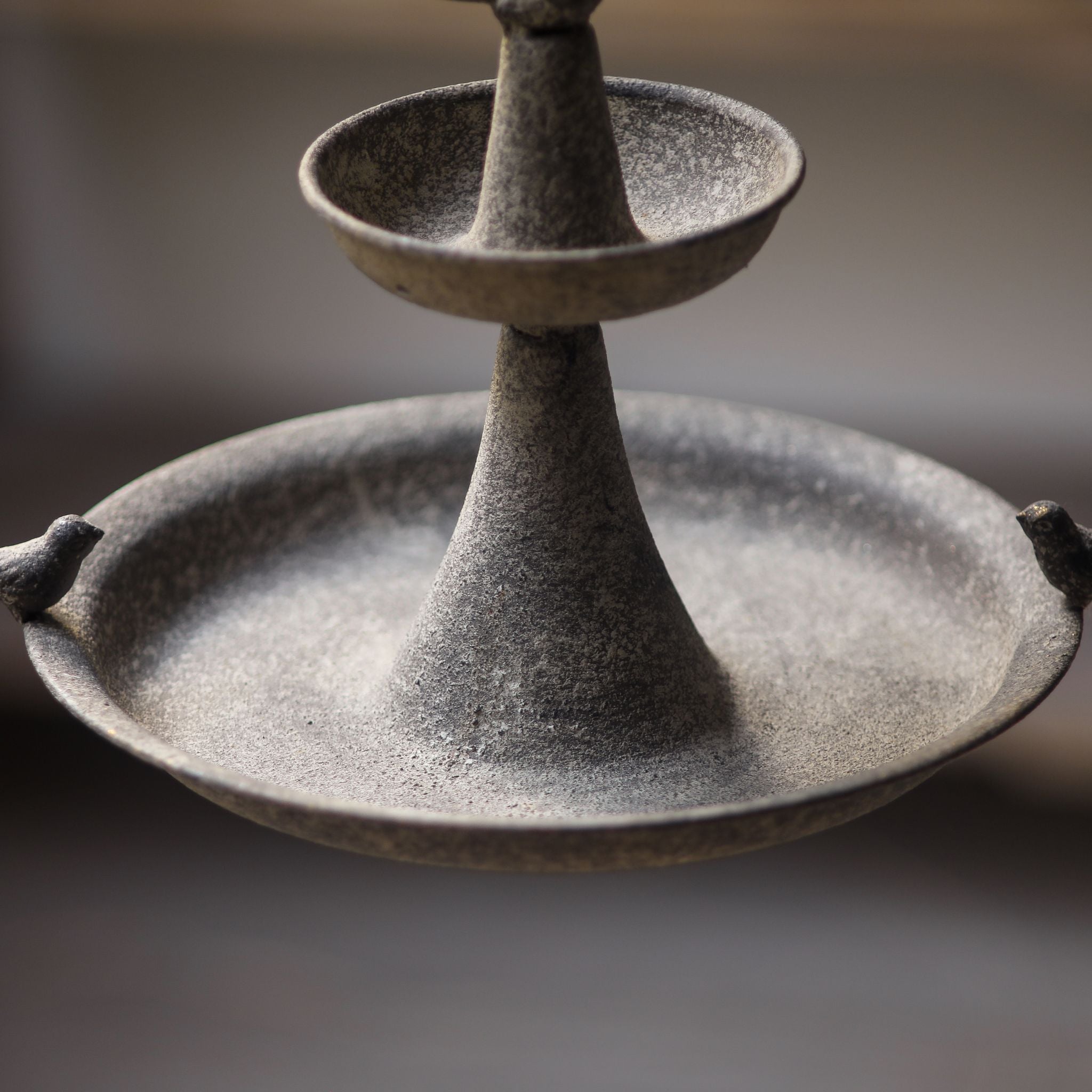 The two dishes and central column of the Penelope hanging feeder against a soft grey background.
