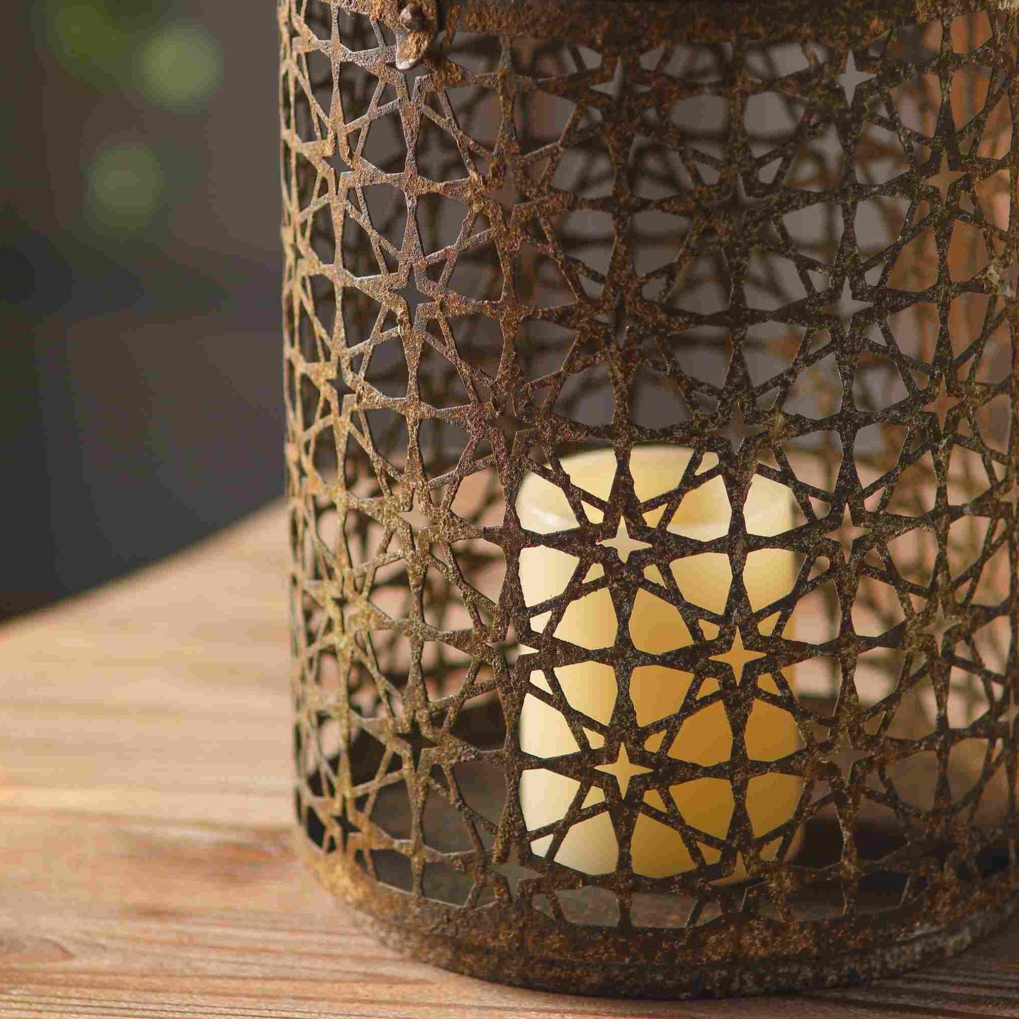 Close detail of the Yannick lantern star-pierced metalwork with warm candlelight glowing through the geometric pattern.