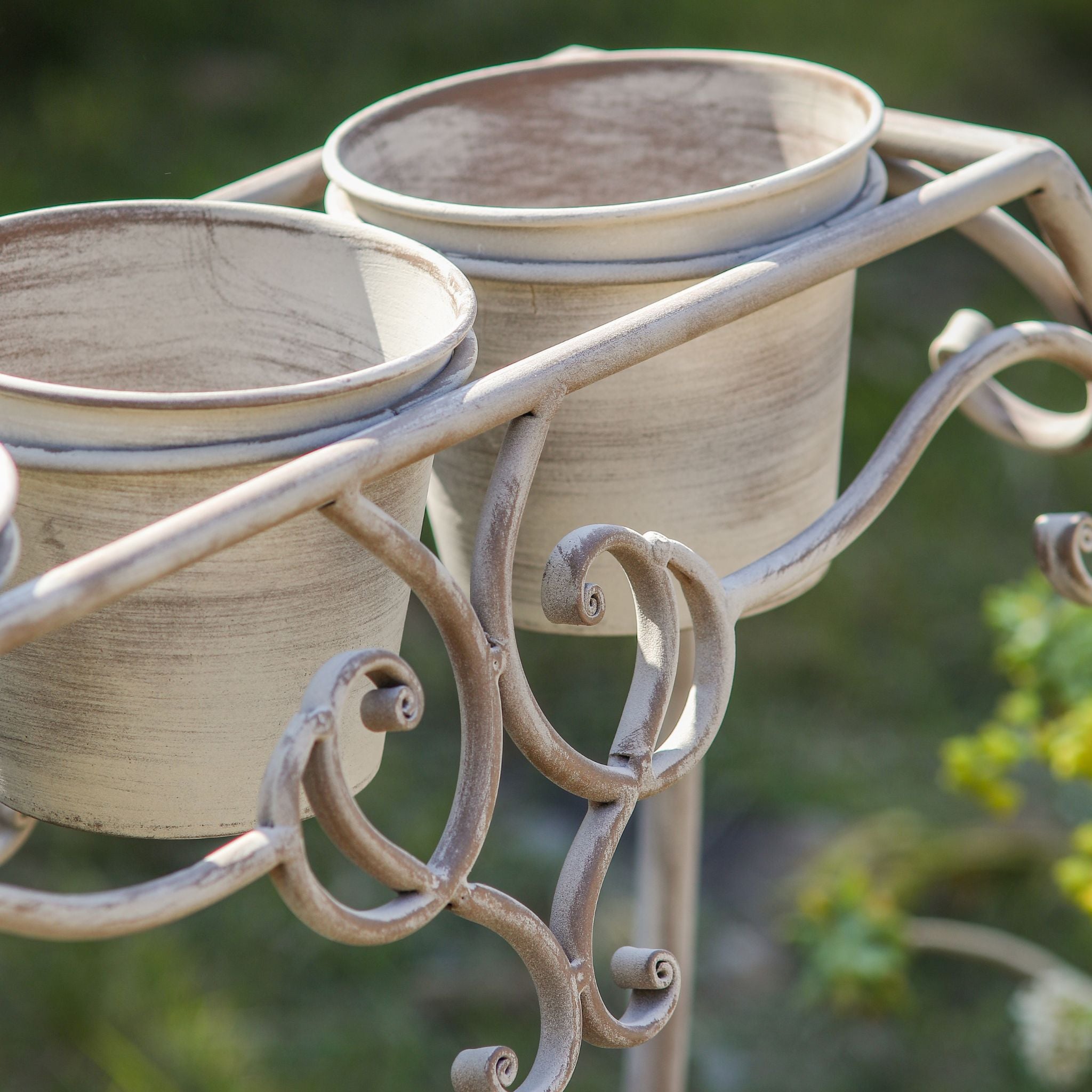 Close-up of two removable pots sitting in the scrolled metal holders of the Yolande stand.
